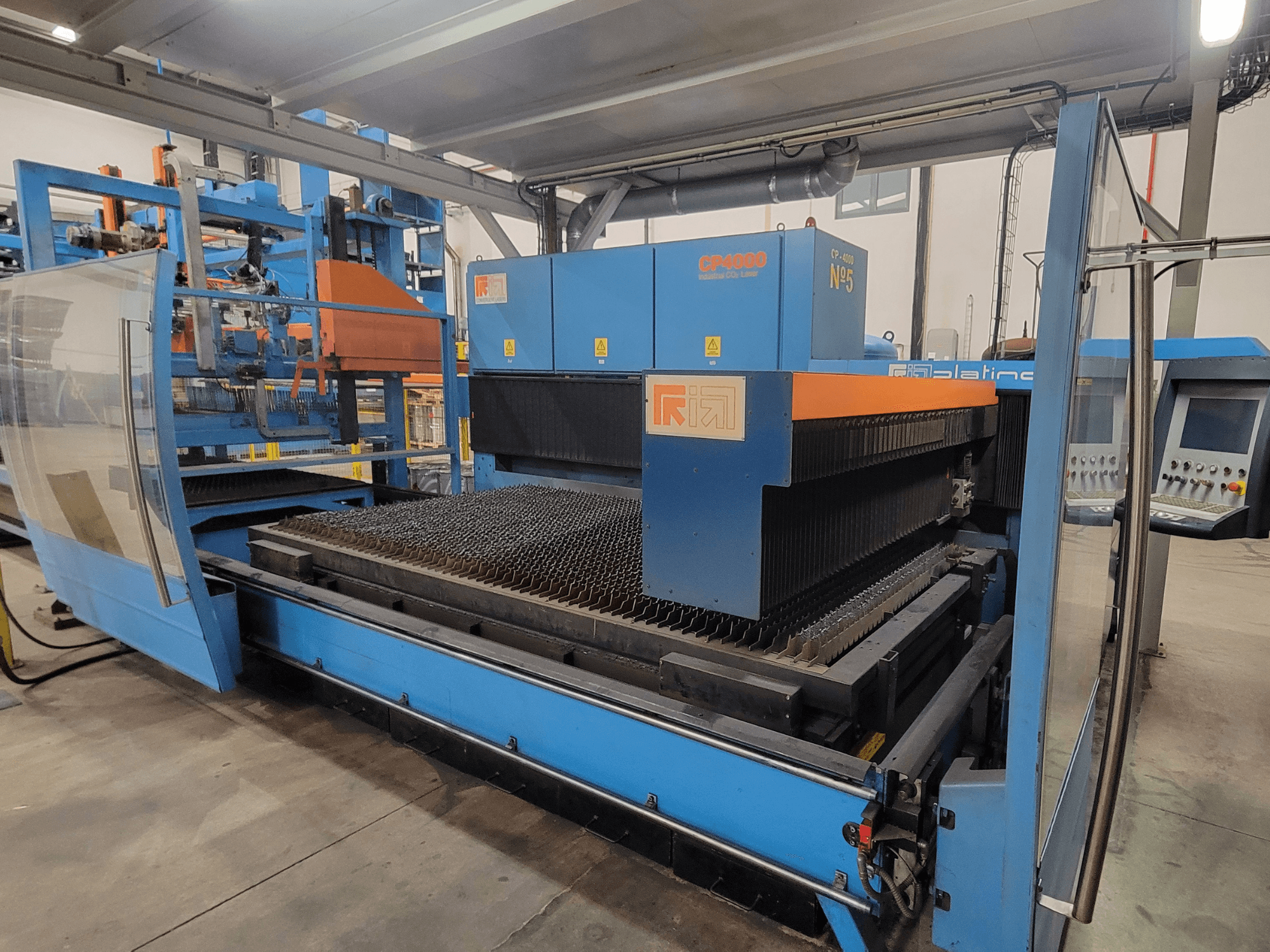 Máquina de corte por láser RIK CP4060 de color azul, vista lateral que muestra la rejilla de corte de metal y el panel de control. Ideal para aplicaciones industriales.