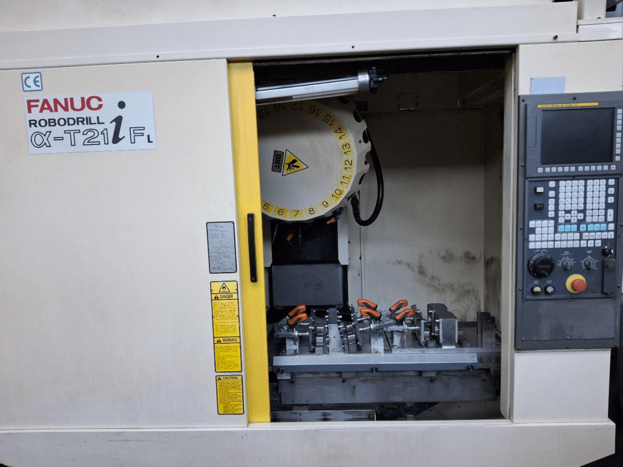 Centro de mecanizado vertical FANUC ROBODRILL α-T21iFL vista frontal, mostrando herramientas y controles dentro del armario de la máquina.