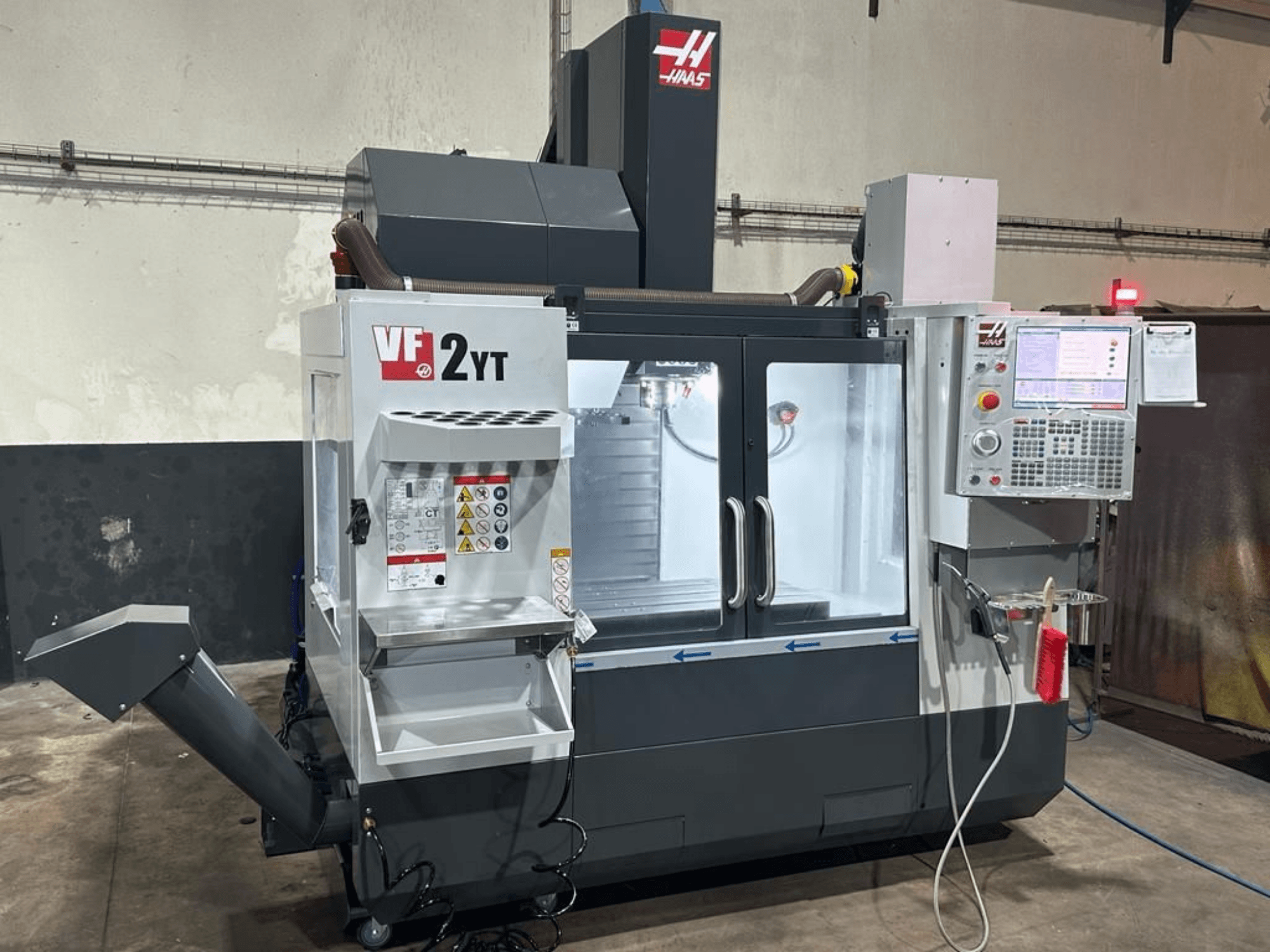 Centro de mecanizado vertical HAAS VF-2YT-EU visto de frente, en el que se aprecian el panel de control y el compartimento de almacenamiento de herramientas.