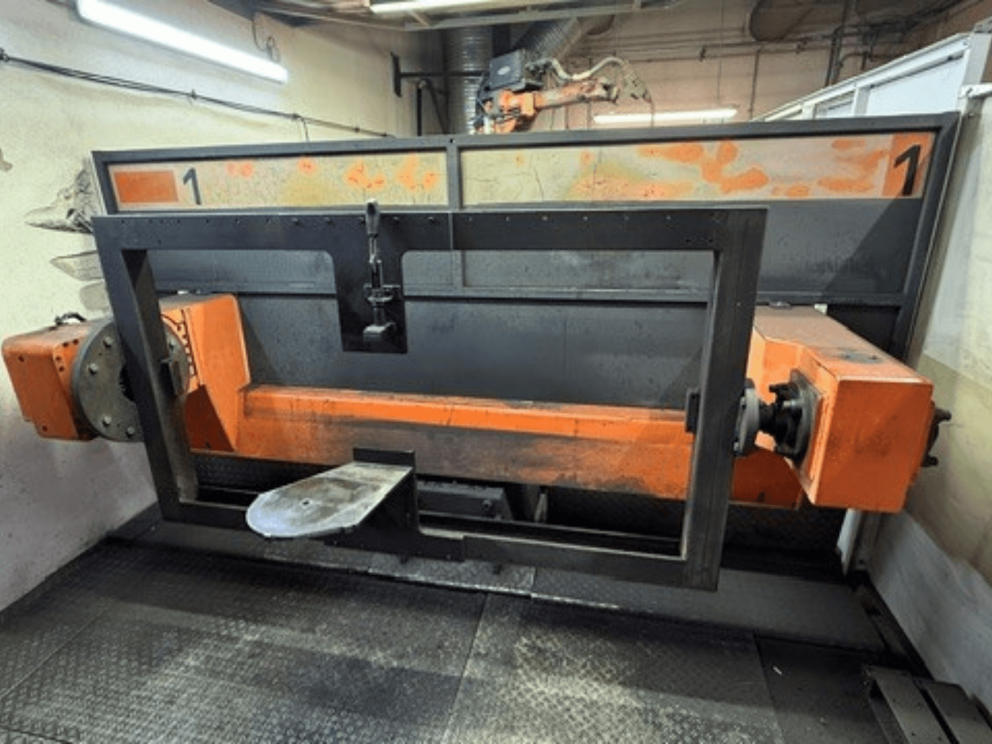 Vista frontal de la célula de soldadura ABB IRB 2400L, en la que se aprecia un gran bastidor robótico con componentes de color naranja y negro en un entorno de taller.