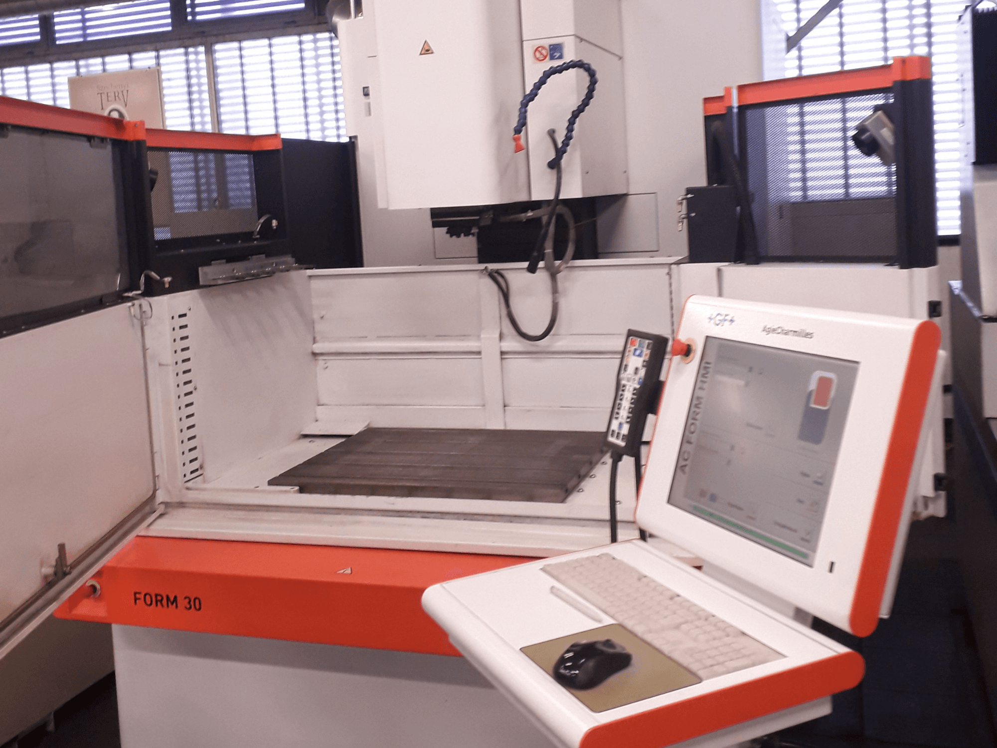 Máquina de electroerosión por penetración FORM 30 de AgieCharmilles mostrada desde una vista frontal con un panel de control y zona de trabajo en el interior.