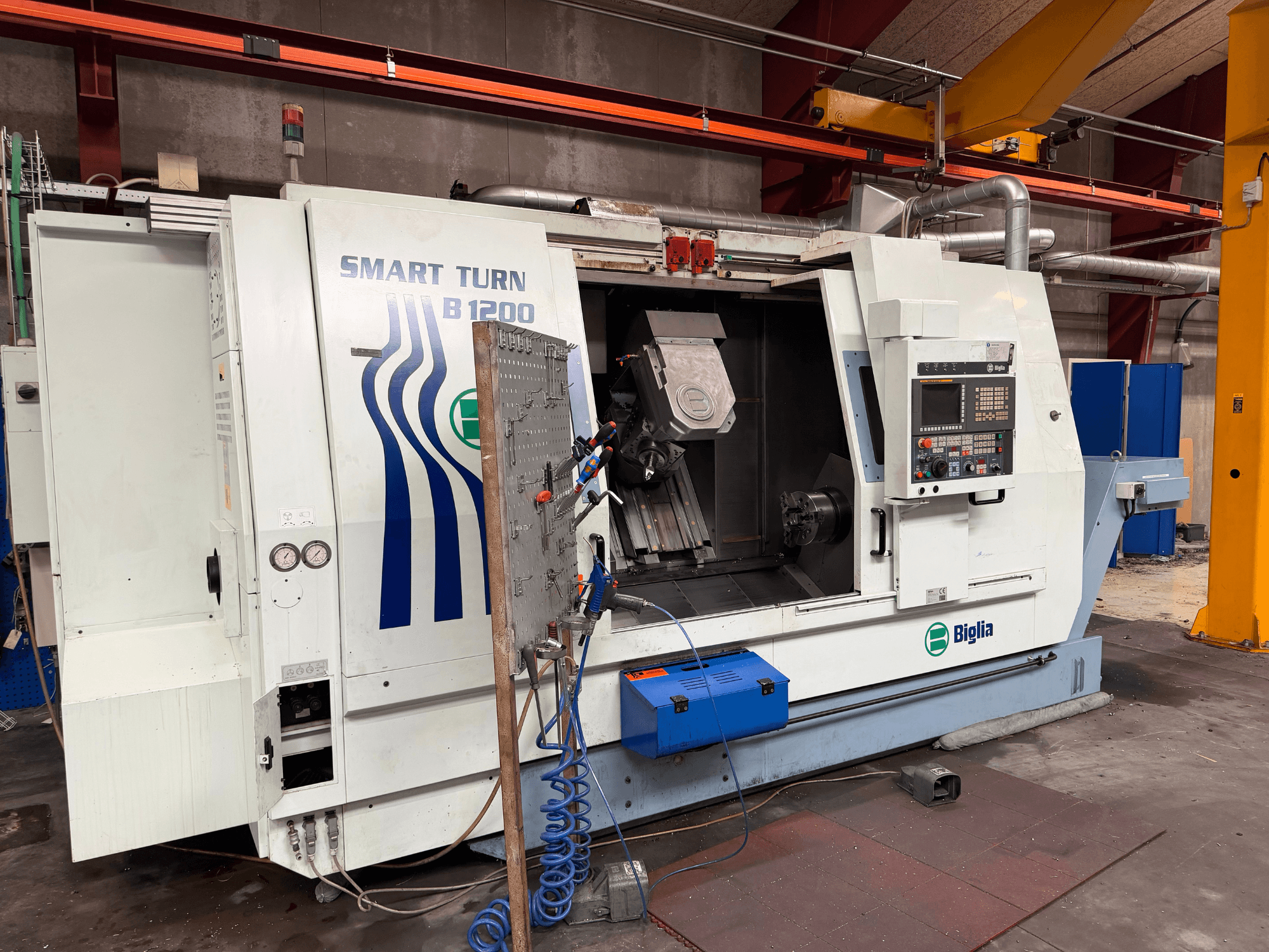 Centro de torneado y fresado Biglia B.1200/S-Smart, visto de frente; muestra los mandos, una pieza de trabajo en el husillo y los manómetros.