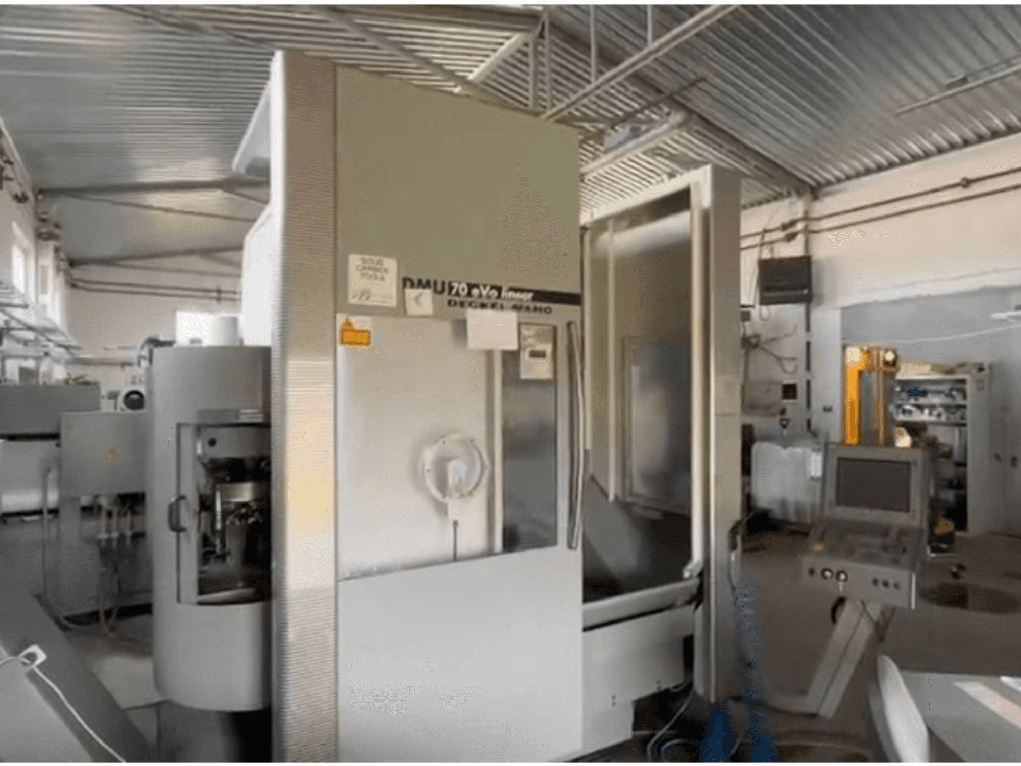 Máquina CNC lineal DMU 70 eVo en un taller, vista frontal, con panel de control y diseño moderno.