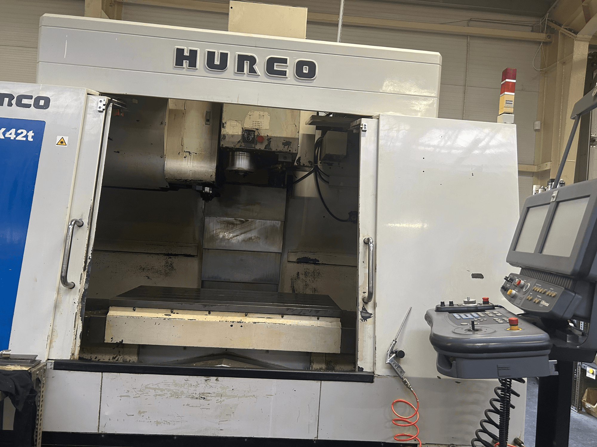 Fresadora CNC Hurco VMX42T en vista frontal, con espacio de trabajo abierto y panel de control con botones y pantalla.