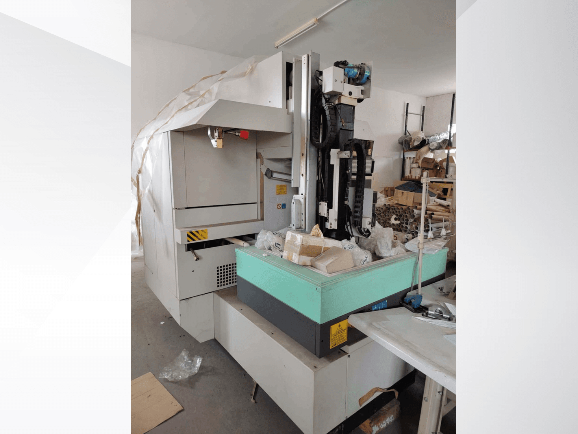 Máquina de electroerosión por penetración AGIE AGIETRON INTEGRAL 2 en vista lateral, con una mesa de trabajo verde y varias herramientas.