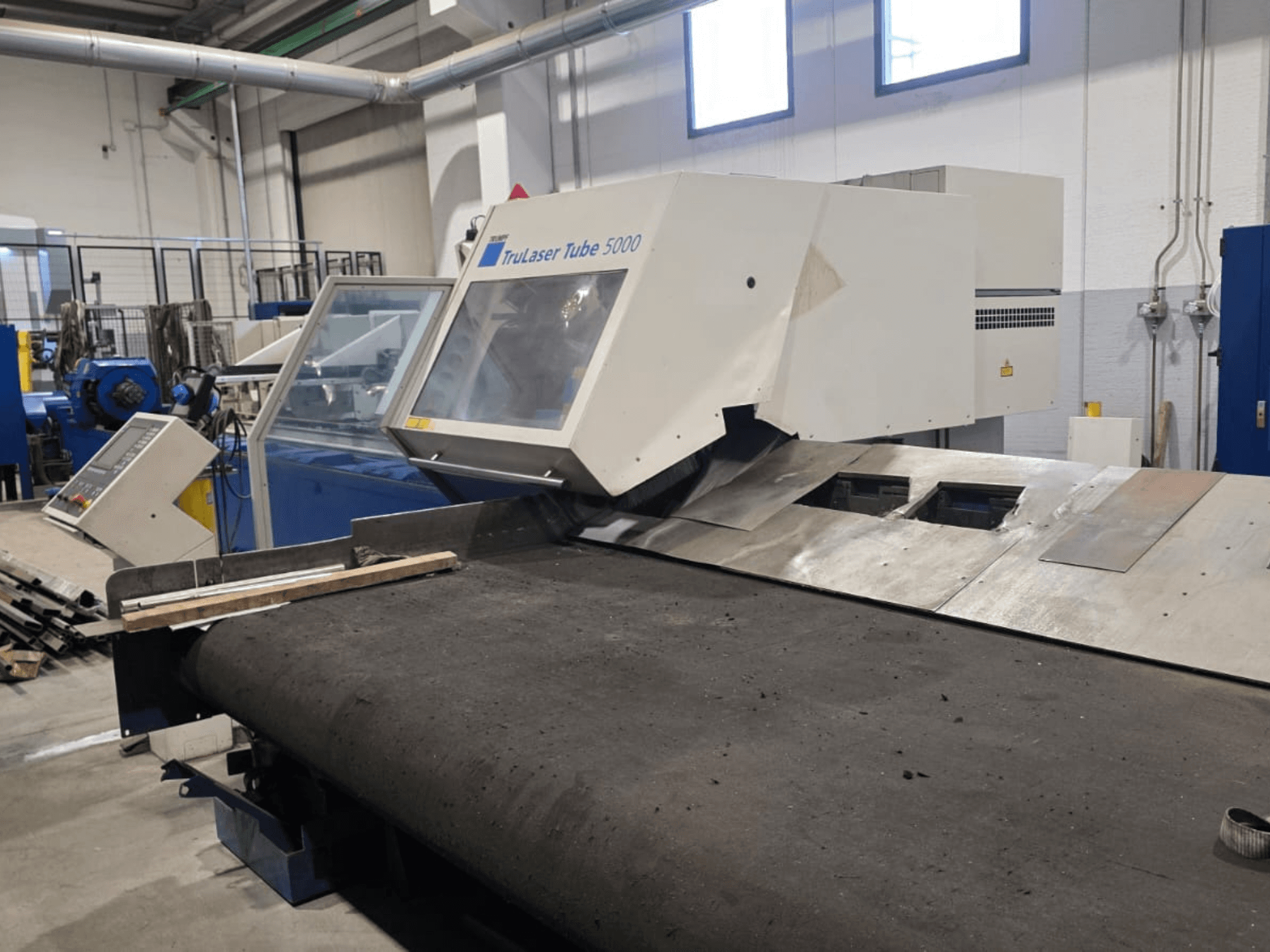 Máquina de corte de tubos TRUMPF LASERTUBE 5000, vista desde delante, en la que se aprecian la zona de corte y el panel de control.