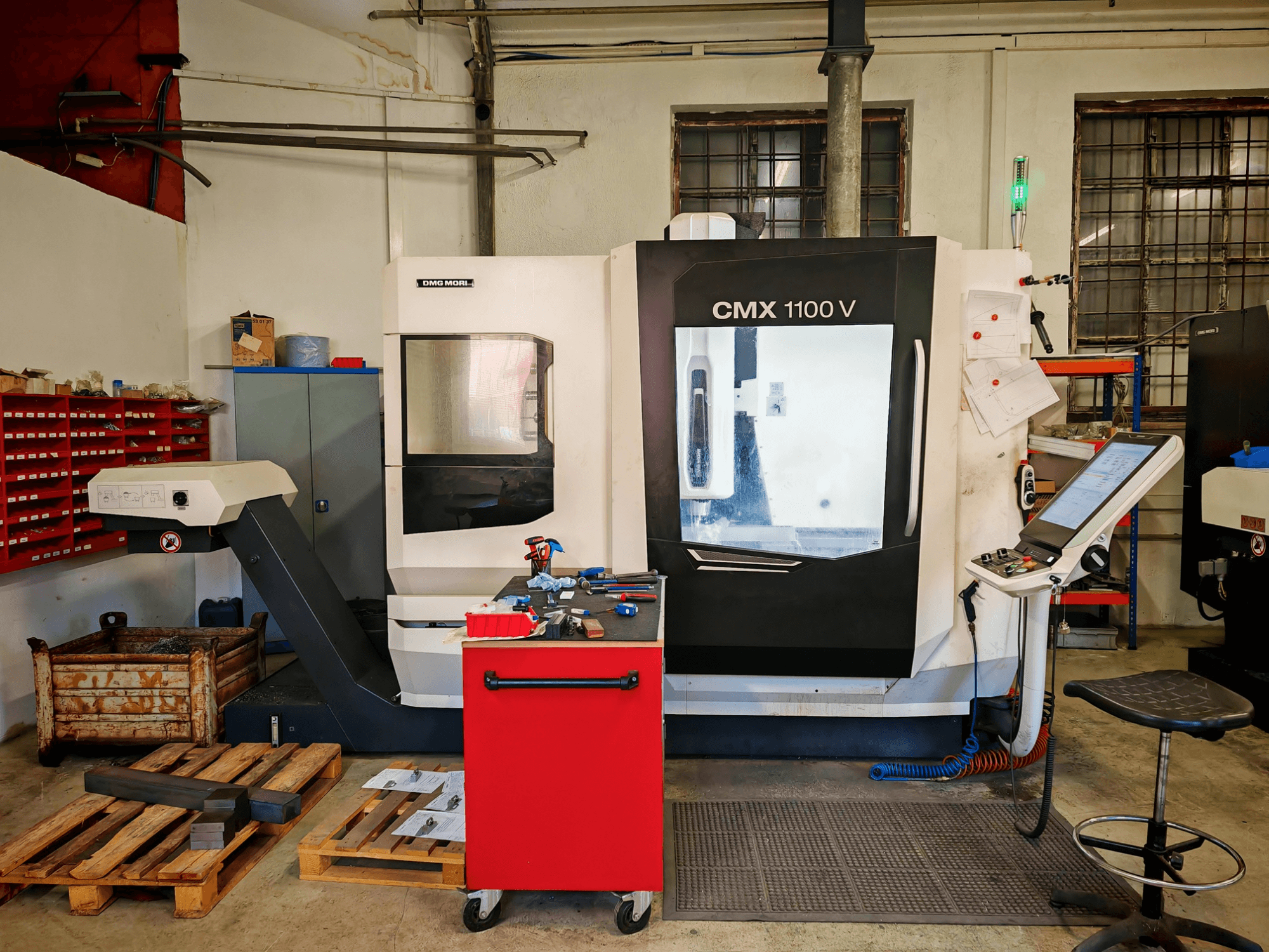 Centro de mecanizado vertical DMG MORI CMX 1100 V en el taller, vista frontal, en la que se aprecian el panel de control y las herramientas que lo rodean.