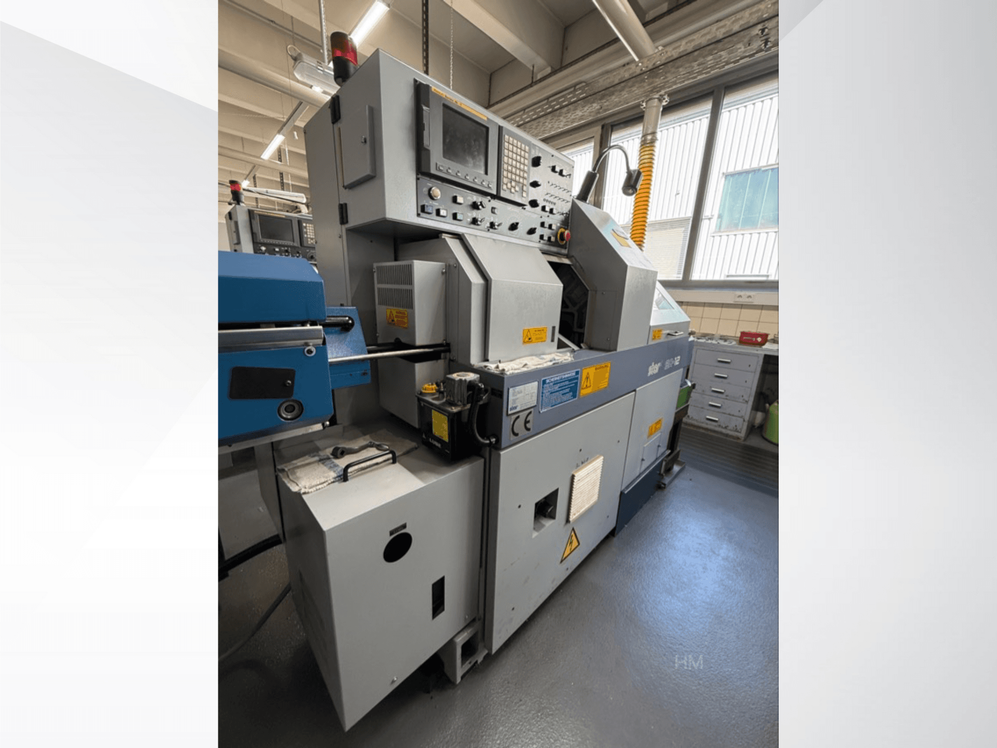 Vista frontal de la máquina lithec 3231, mostrando el panel de control, el motor y la sección de alimentación azul en un entorno industrial bien iluminado.