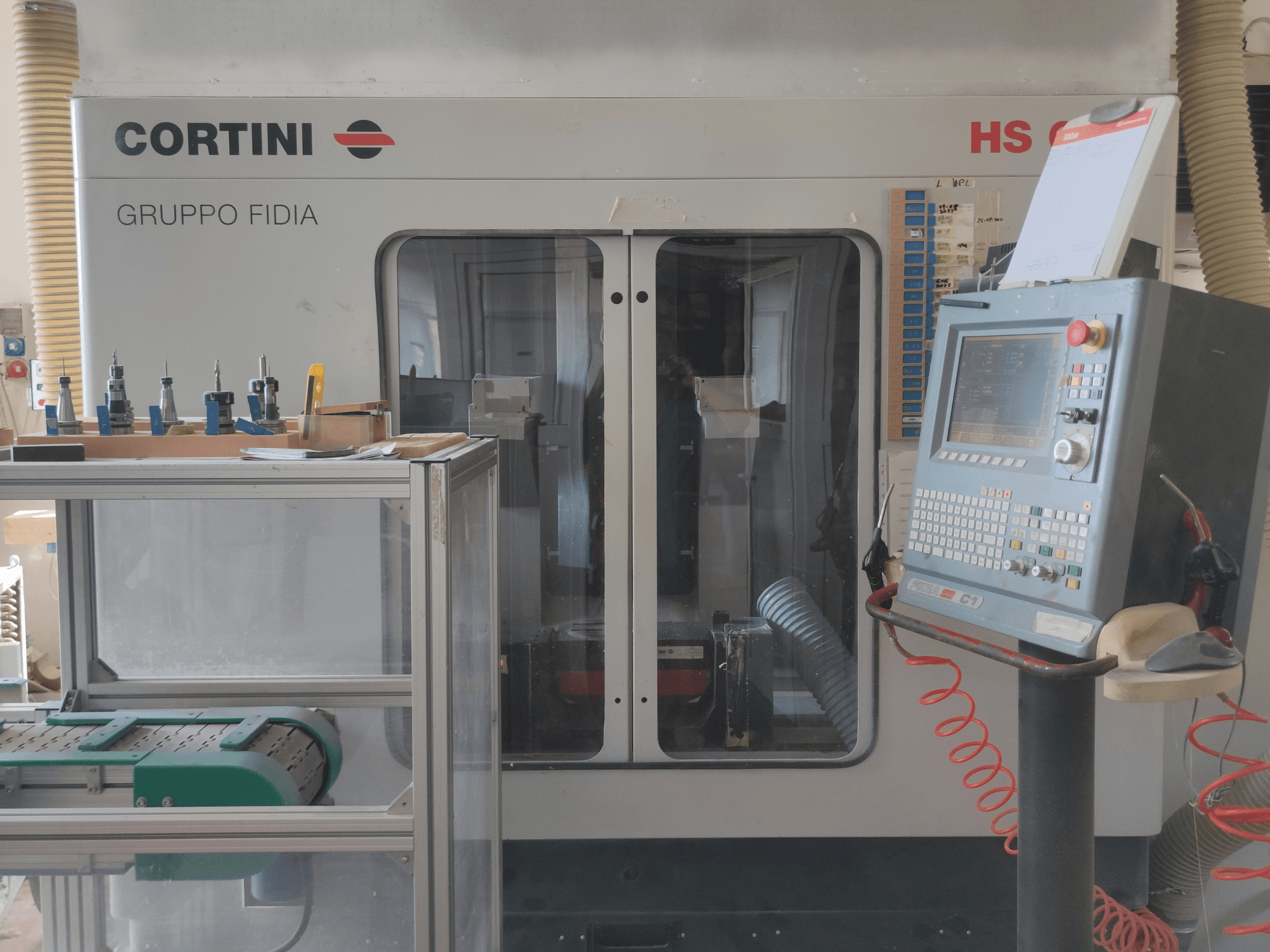 Vista frontal del centro de mecanizado vertical CORTINI HS 644, con el panel de control, las herramientas expuestas y los componentes visibles de la maquinaria.