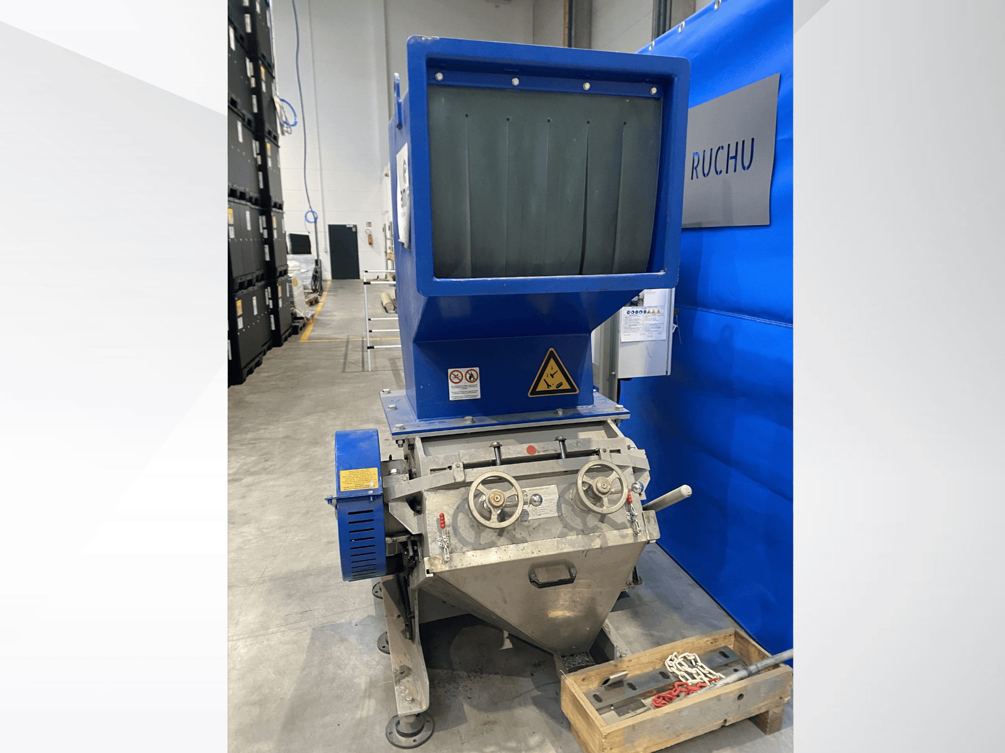 Vista frontal de la máquina de procesamiento de plástico AMIS GSE 300/600 con tolva azul, mandos de control y etiquetas de advertencia.