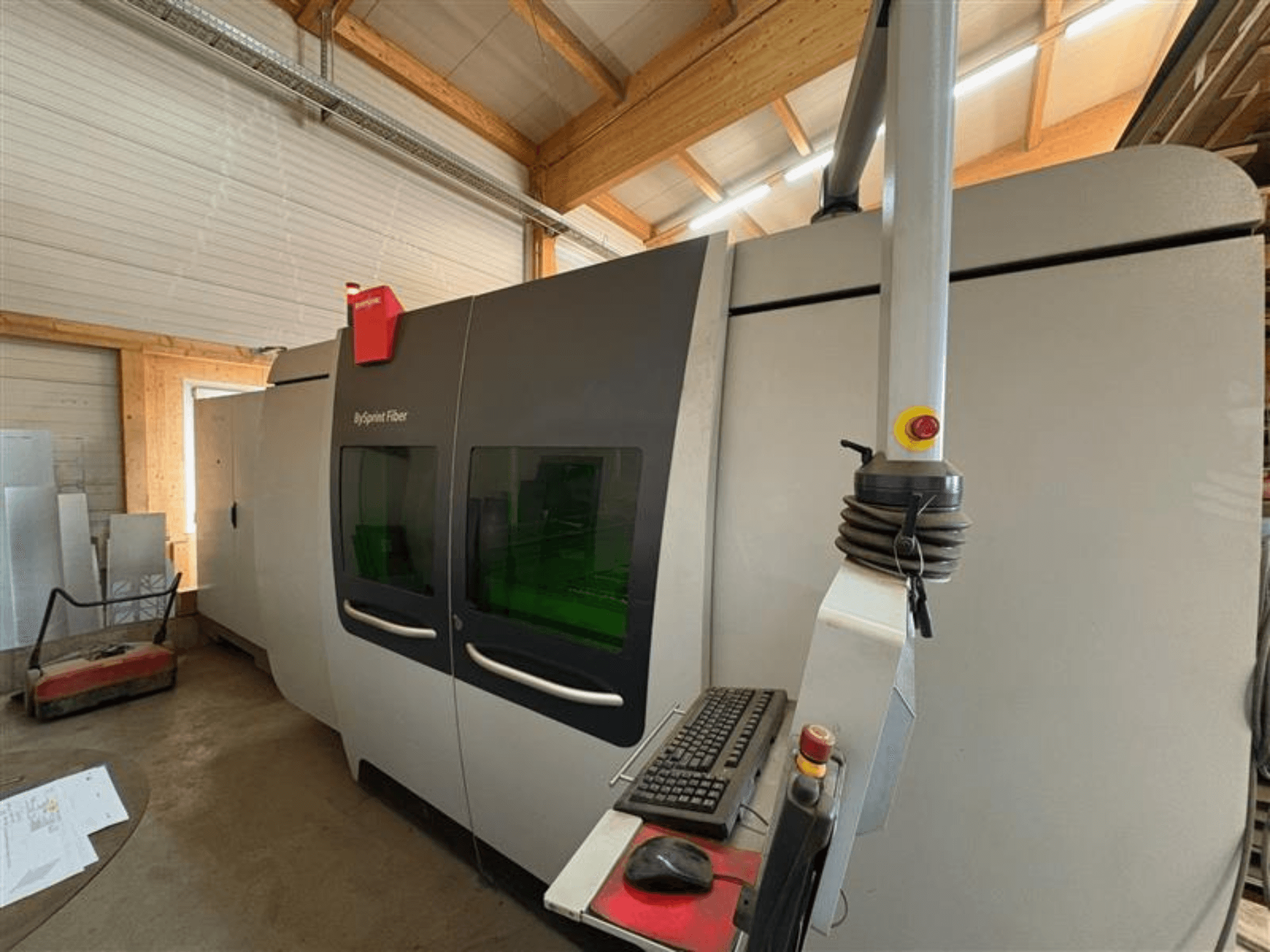 Máquina de corte de fibra Bystronic ByJet Fiber en un taller, vista frontal que muestra el panel de control y las ventanas de visualización verdes dobles.