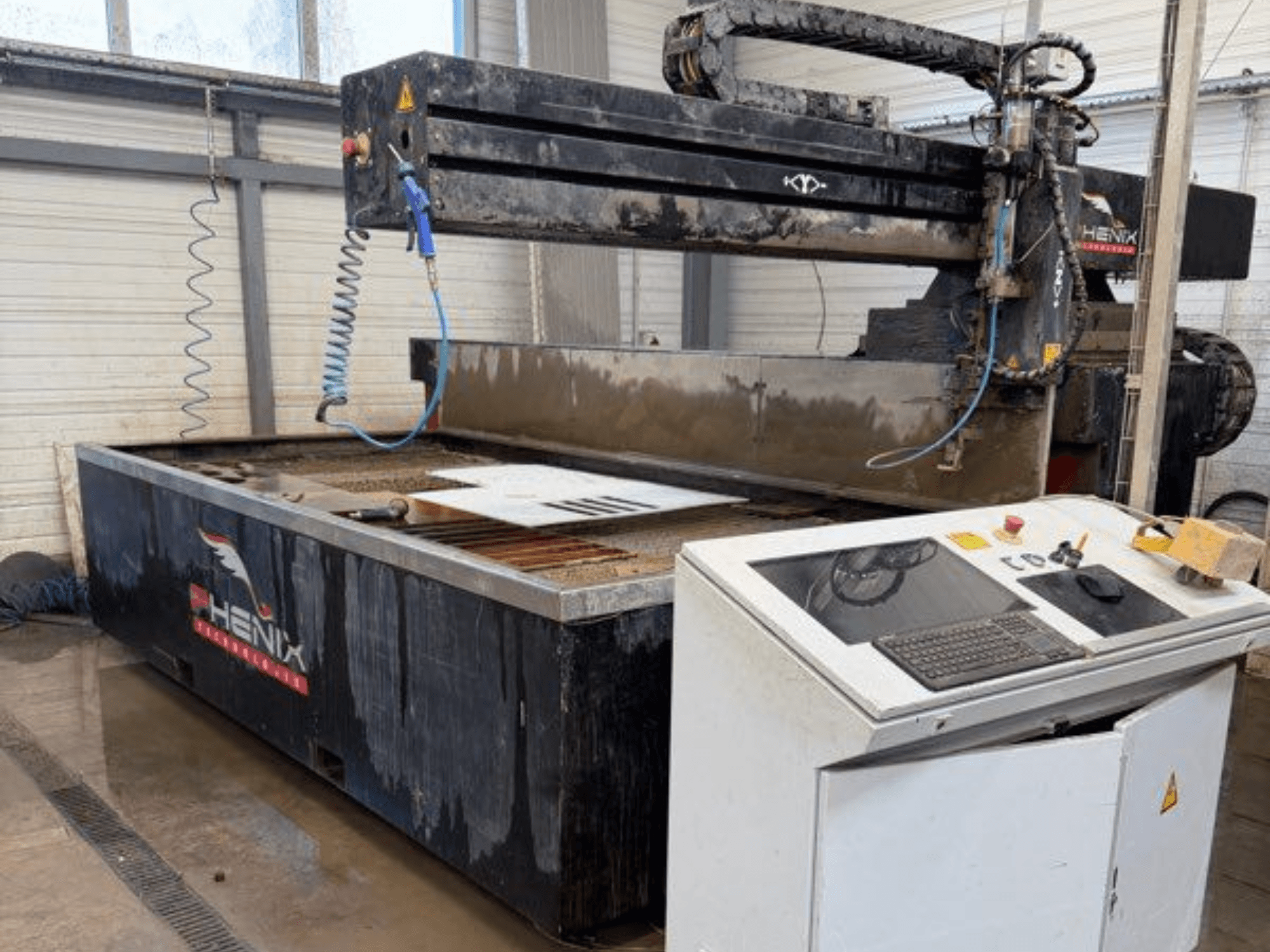 Máquina de corte por chorro de agua PHENIX MD JET 1530, vista frontal que muestra el panel de control y la zona de corte con el depósito de agua visible.