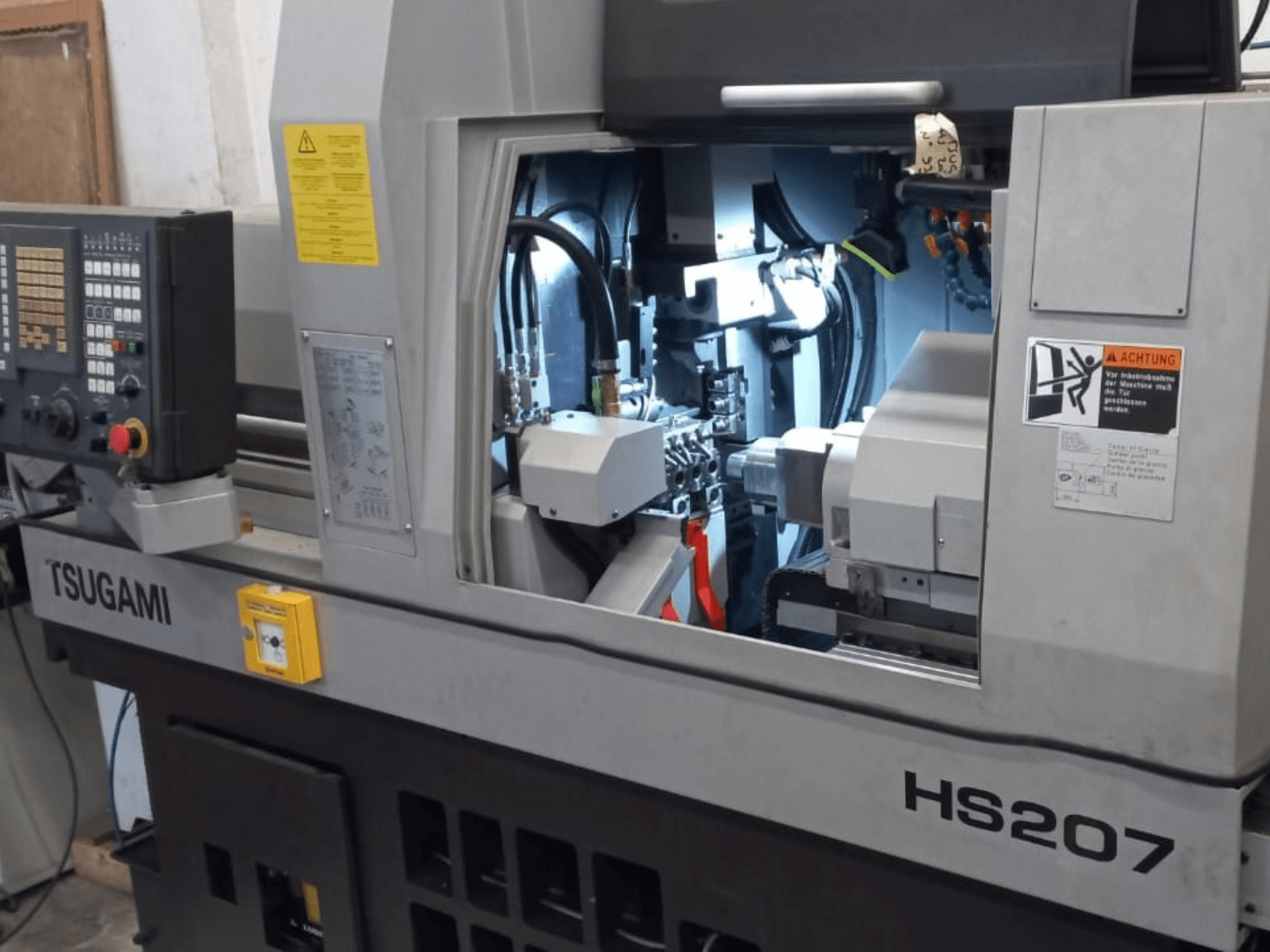 Torno de tipo suizo TSUGAMI HS207; vista frontal en la que se aprecian el panel de control y los componentes internos.