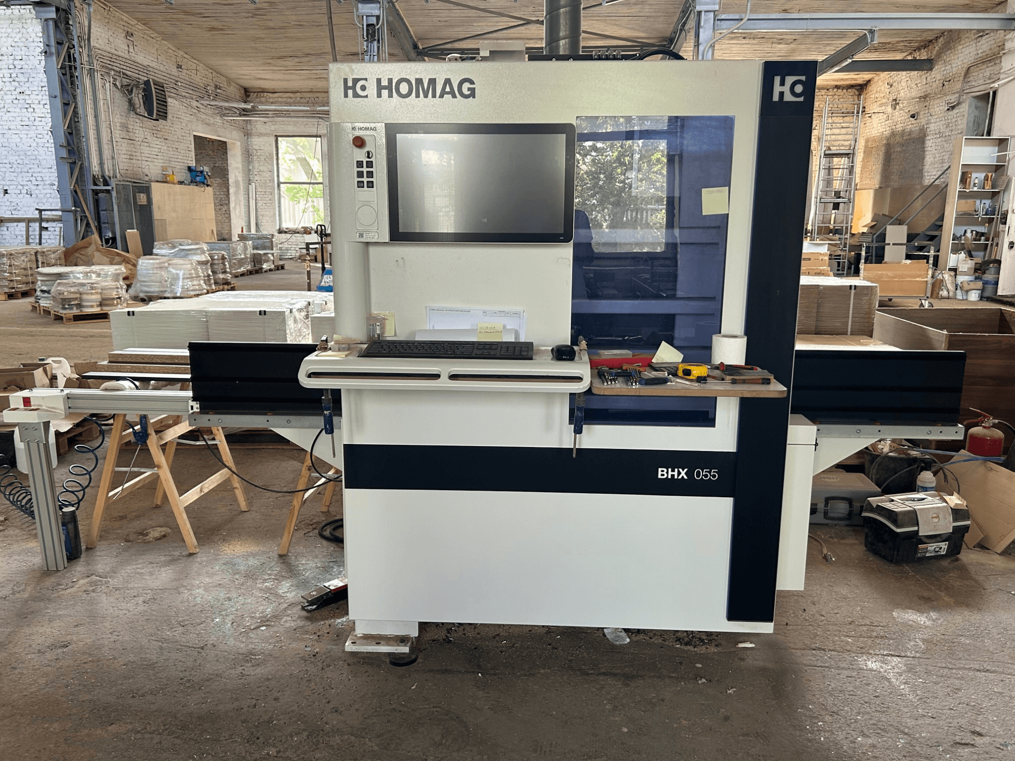 Centro de mecanizado CNC HOMAG WEEKE OPTIMAT BHX 055, vista frontal, en la que se aprecian el panel de control y el espacio de trabajo con las herramientas.