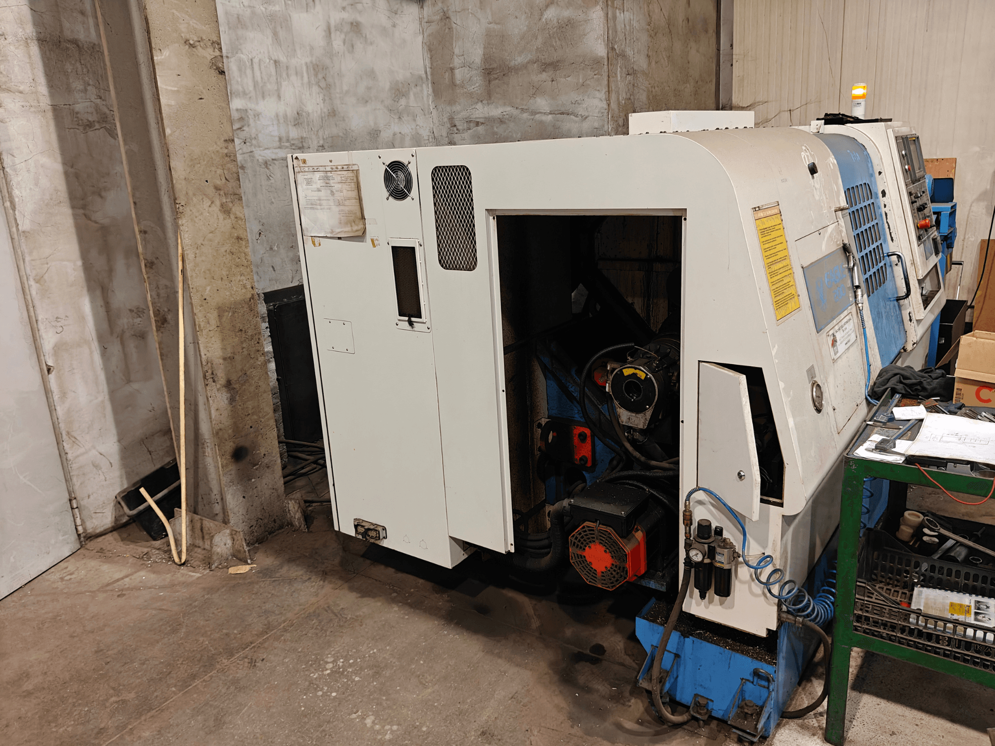 Vista frontal de una máquina de torno, marca y modelo no especificados, con controles y componentes visibles del motor.