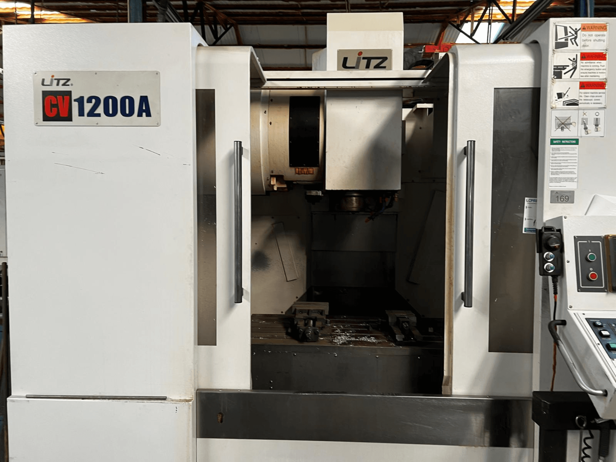 Centro de mecanizado vertical Litz CV1200A, vista frontal, en la que se aprecian el panel de control, el husillo y la puerta abierta que deja a la vista la zona de trabajo.
