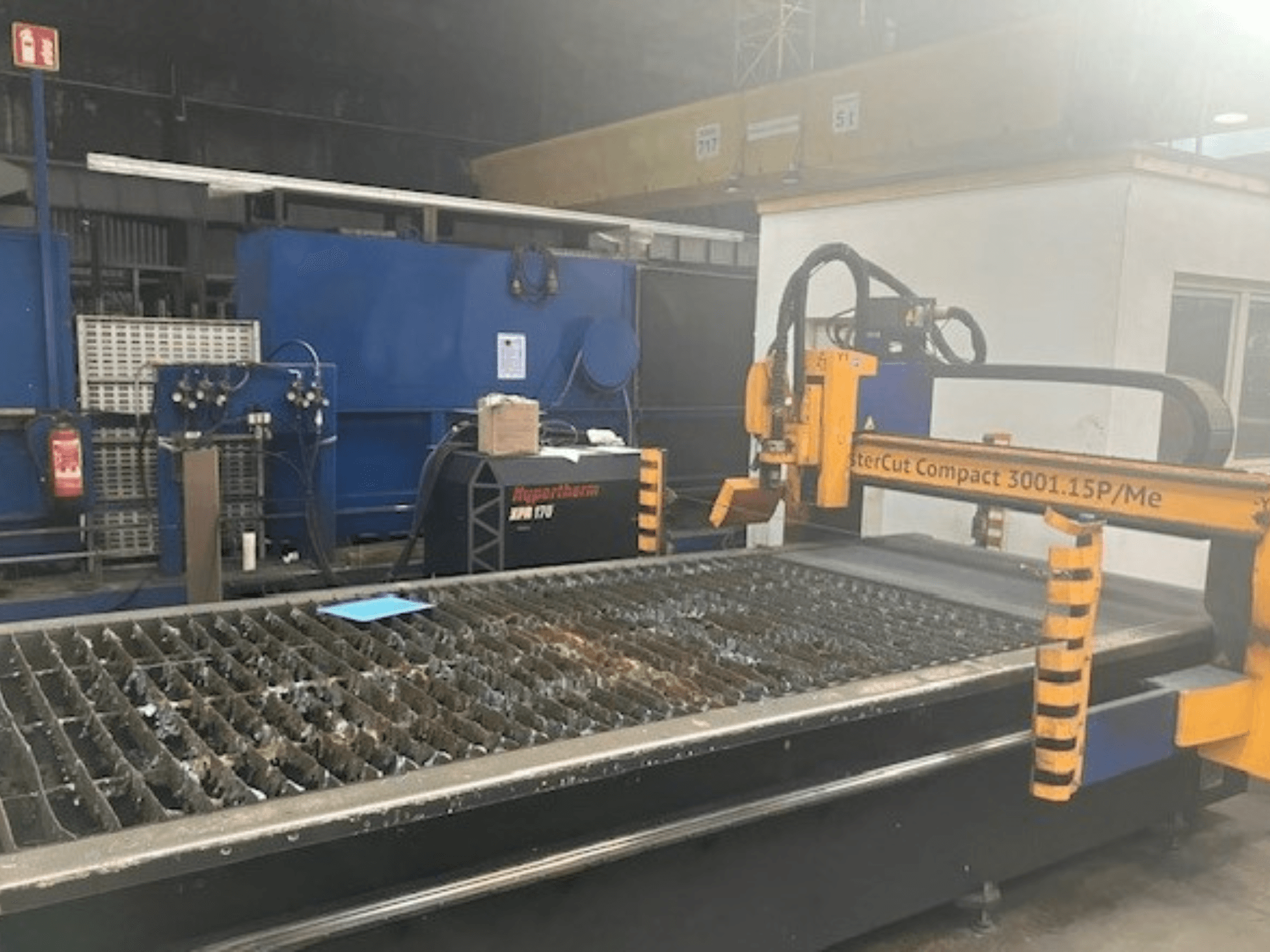 Máquina de corte por plasma Hypertherm MasterCut Compact 3001.15P/Me en vista lateral, mostrando la mesa de corte y el panel de control.