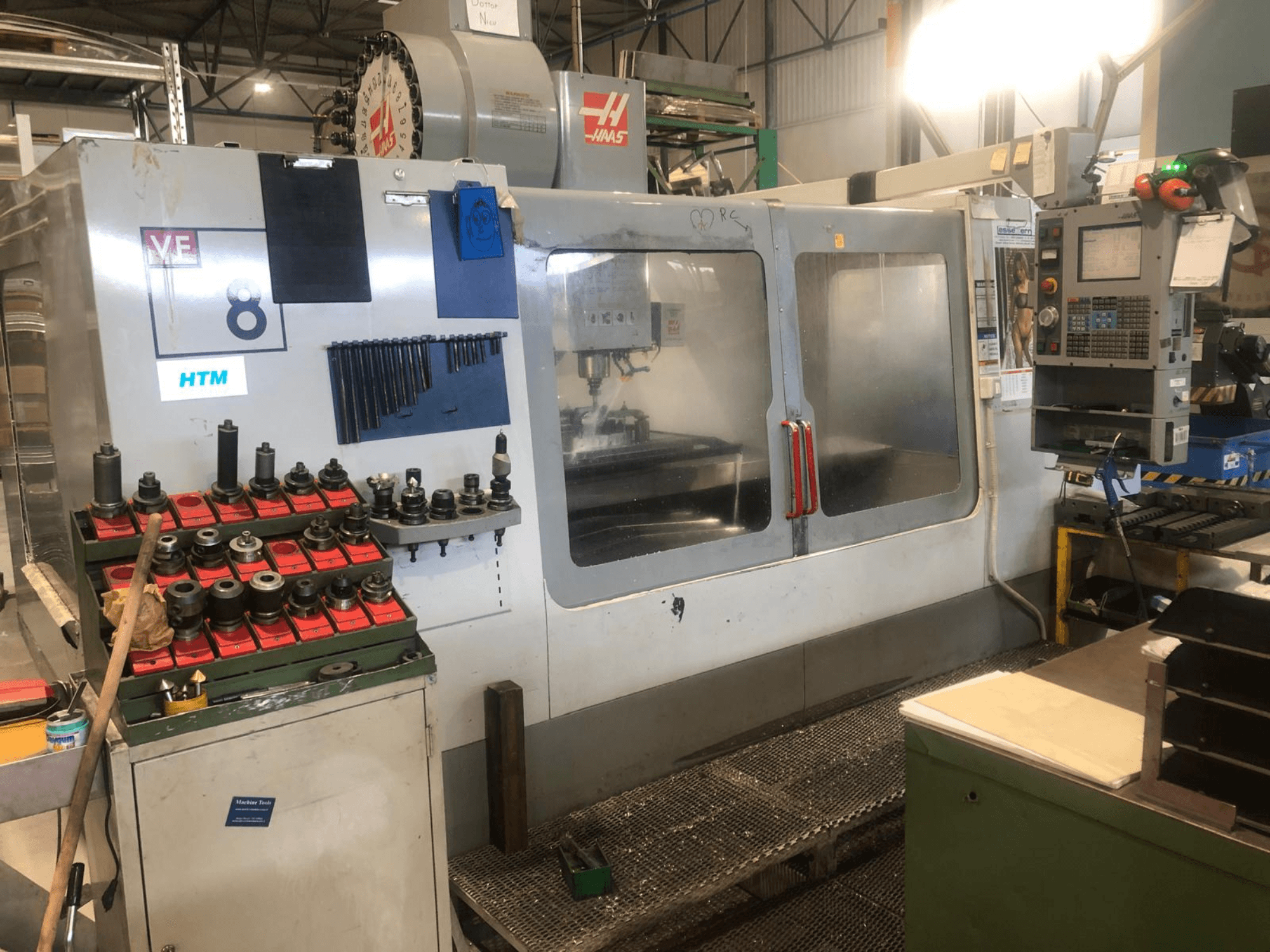Máquina CNC Haas en un taller, vista frontal; muestra herramientas y controles, con detalles visibles del modelo y portaherramientas organizados.