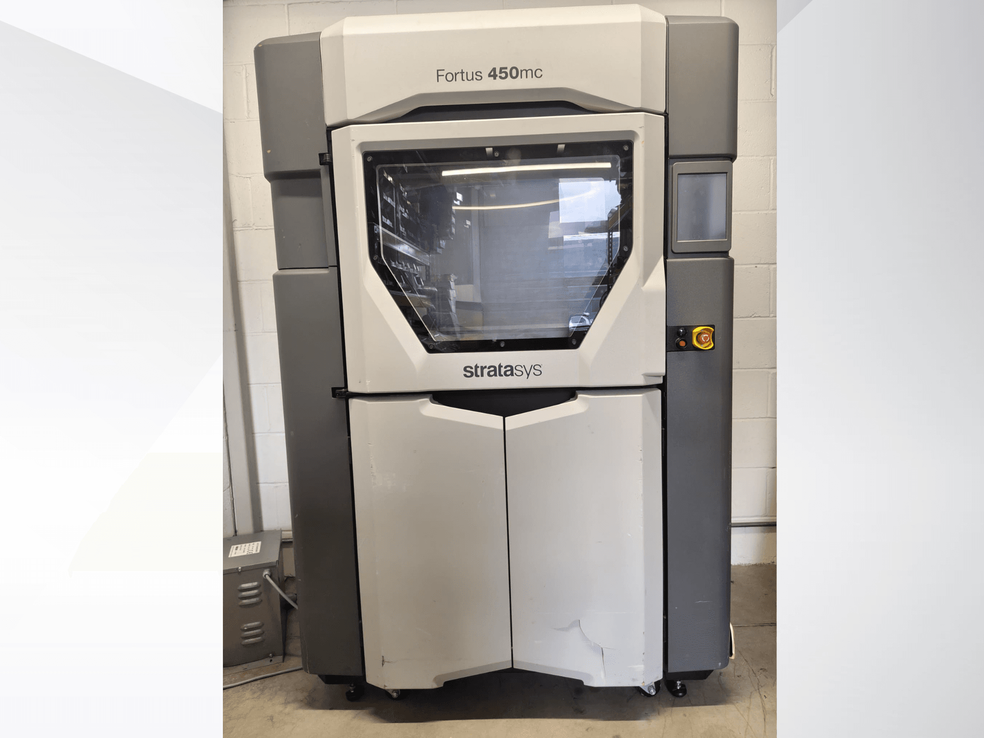 Máquina de procesamiento de plástico Stratasys Fortus 450mc, vista frontal, con una amplia ventana, panel de control y diseño industrial.