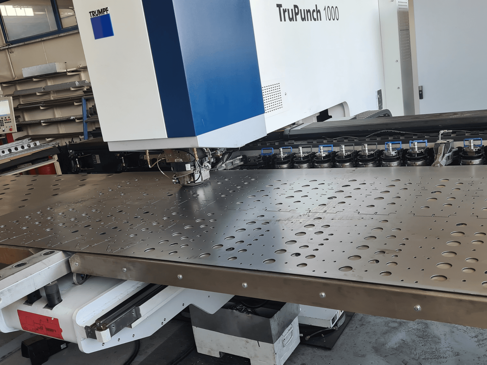 Punzonadora CNC TRUMPF TruPunch 1000, vista frontal, en la que se aprecia una chapa metálica perforada y la configuración de la herramienta.