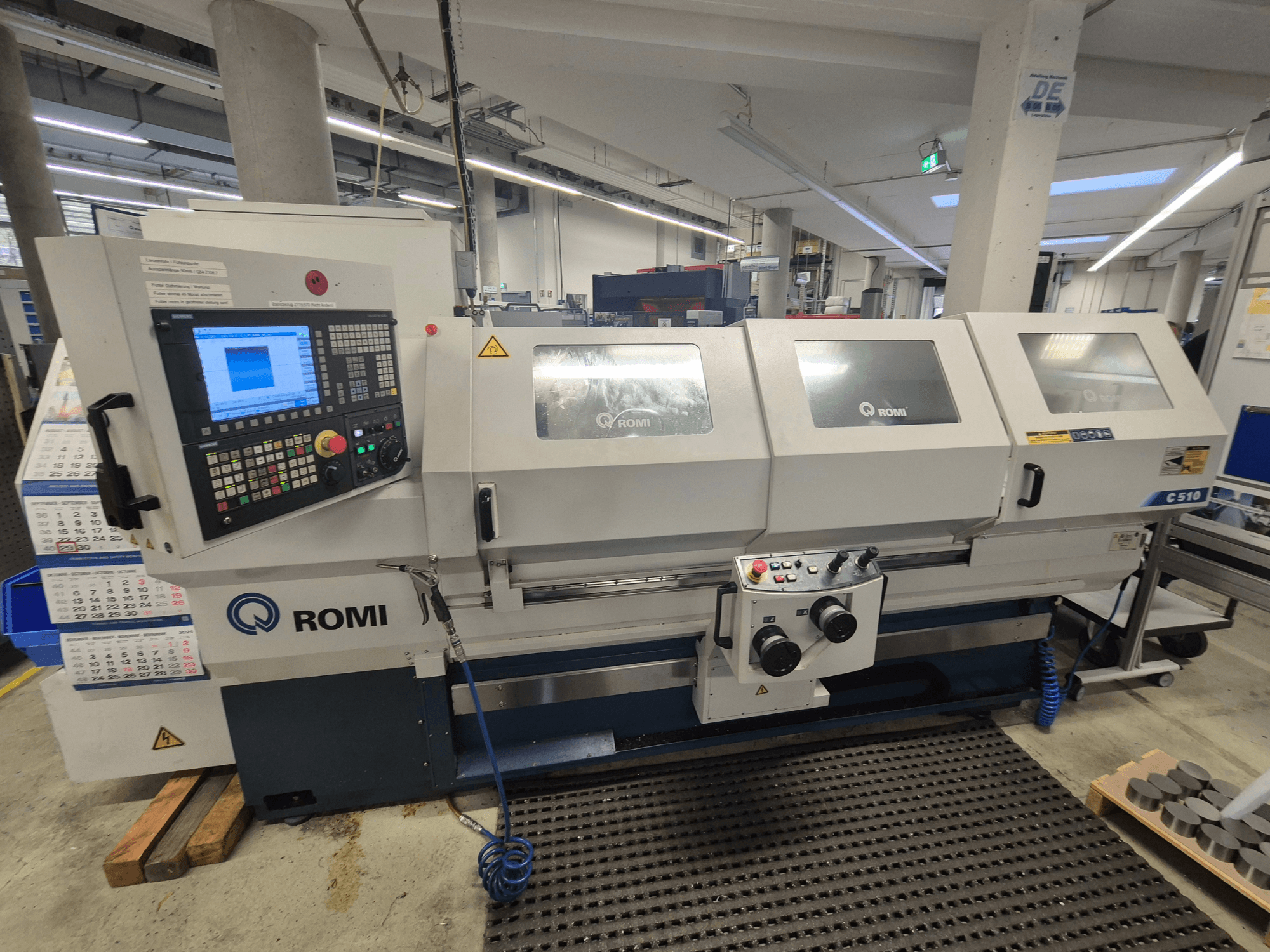 Torno Romi C510 visto de frente, con panel de control digital y tres tapas de protección. Incluye etiquetas de advertencia de seguridad.