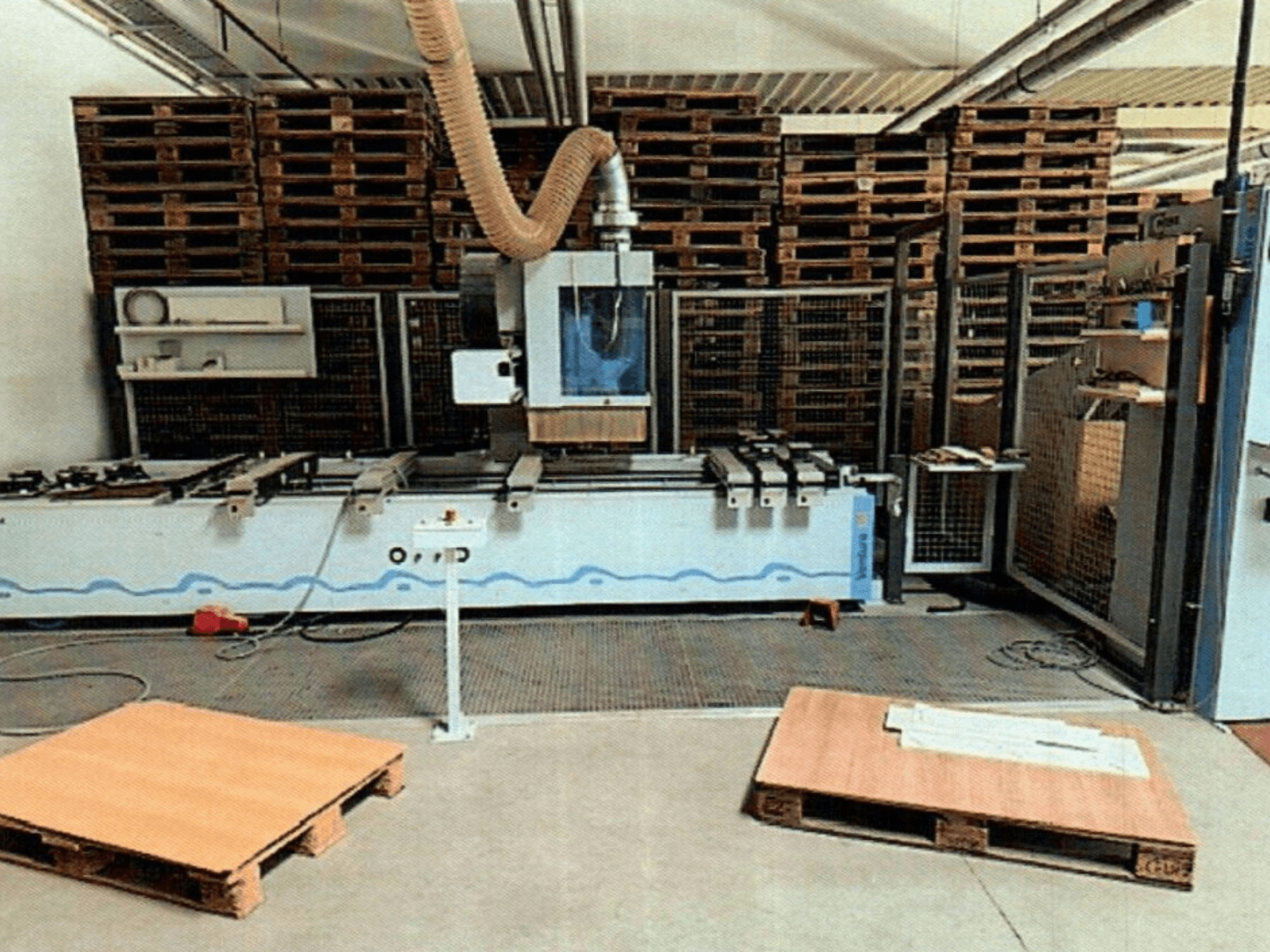 Centro de mecanizado de madera CNC Weeke Venture 1M en un taller, vista frontal con palets de madera visibles y configuración industrial.