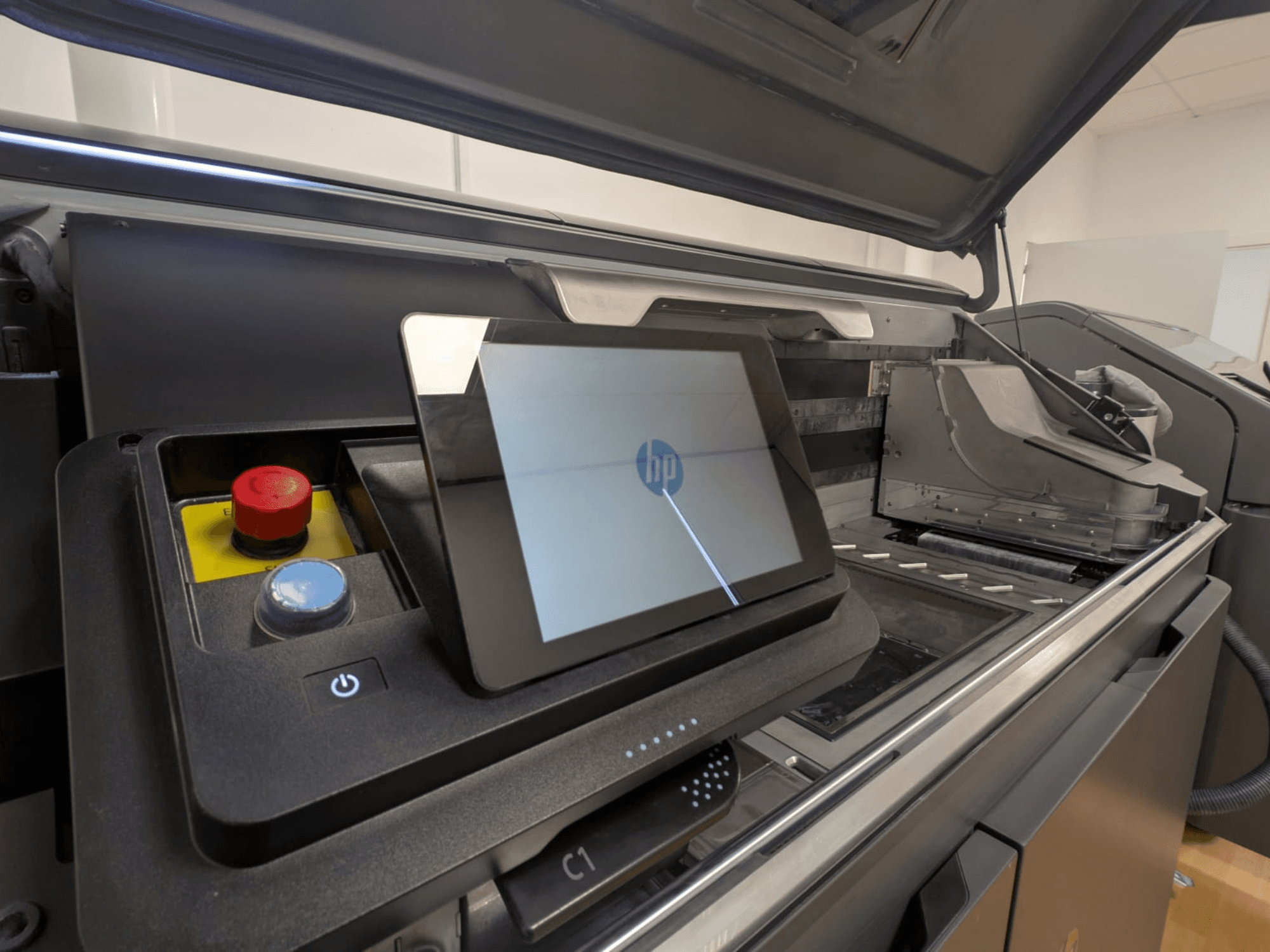 Panel de control de la impresora HP que muestra una pantalla de tableta, botones rojos y azules, y una vista lateral de los componentes interiores de la impresora.