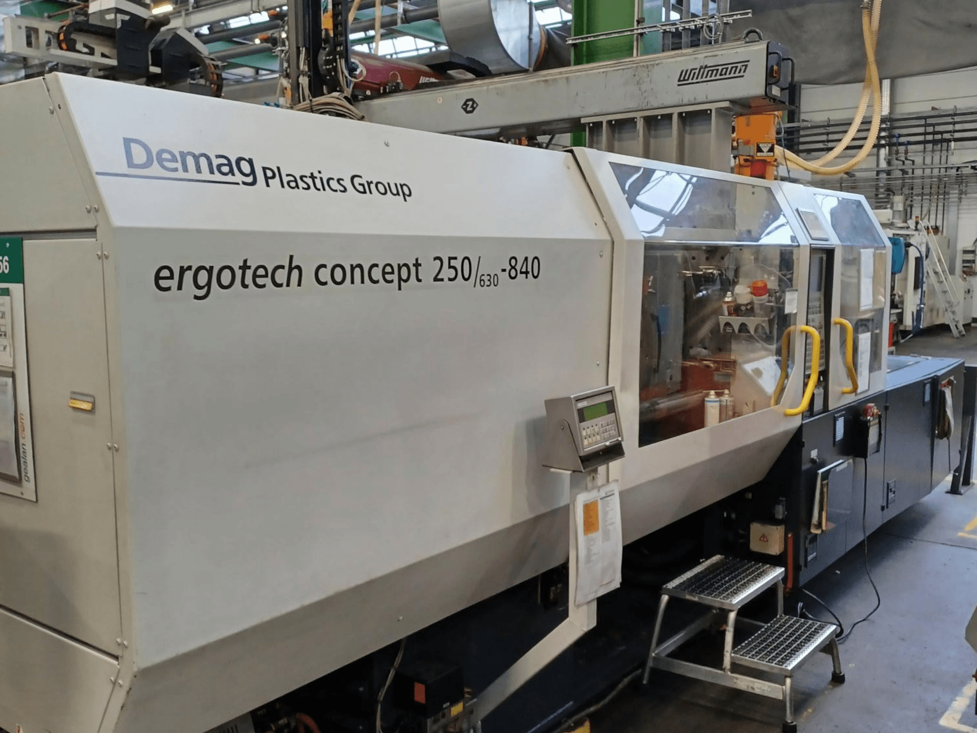 Máquina de moldeo por inyección Demag ergotech concept 250/630-840, vista frontal, mostrando los controles digitales y las cubiertas de seguridad transparentes.