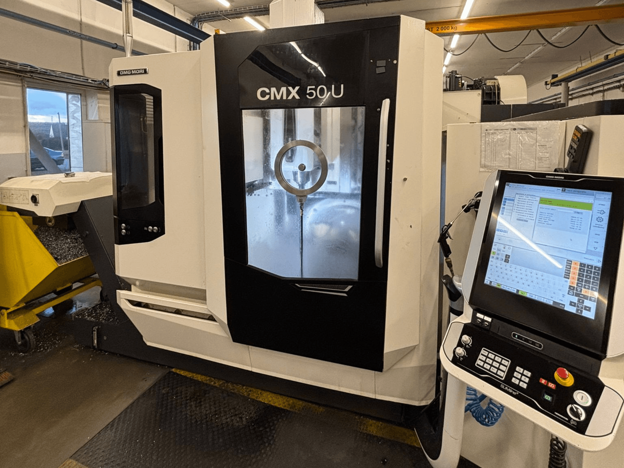 Centro de mecanizado vertical DMG MORI CMX 50 U, vista frontal con panel de control y pantalla de cristal, mostrando la mecánica interna.