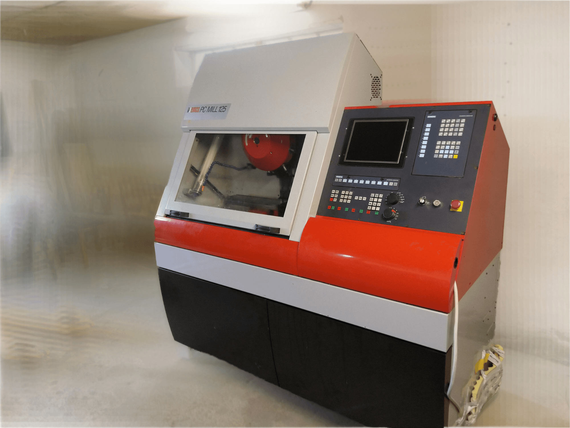 Centro de mecanizado vertical EMCO PC MILL 125, vista frontal con panel de control y zona de mecanizado visible.