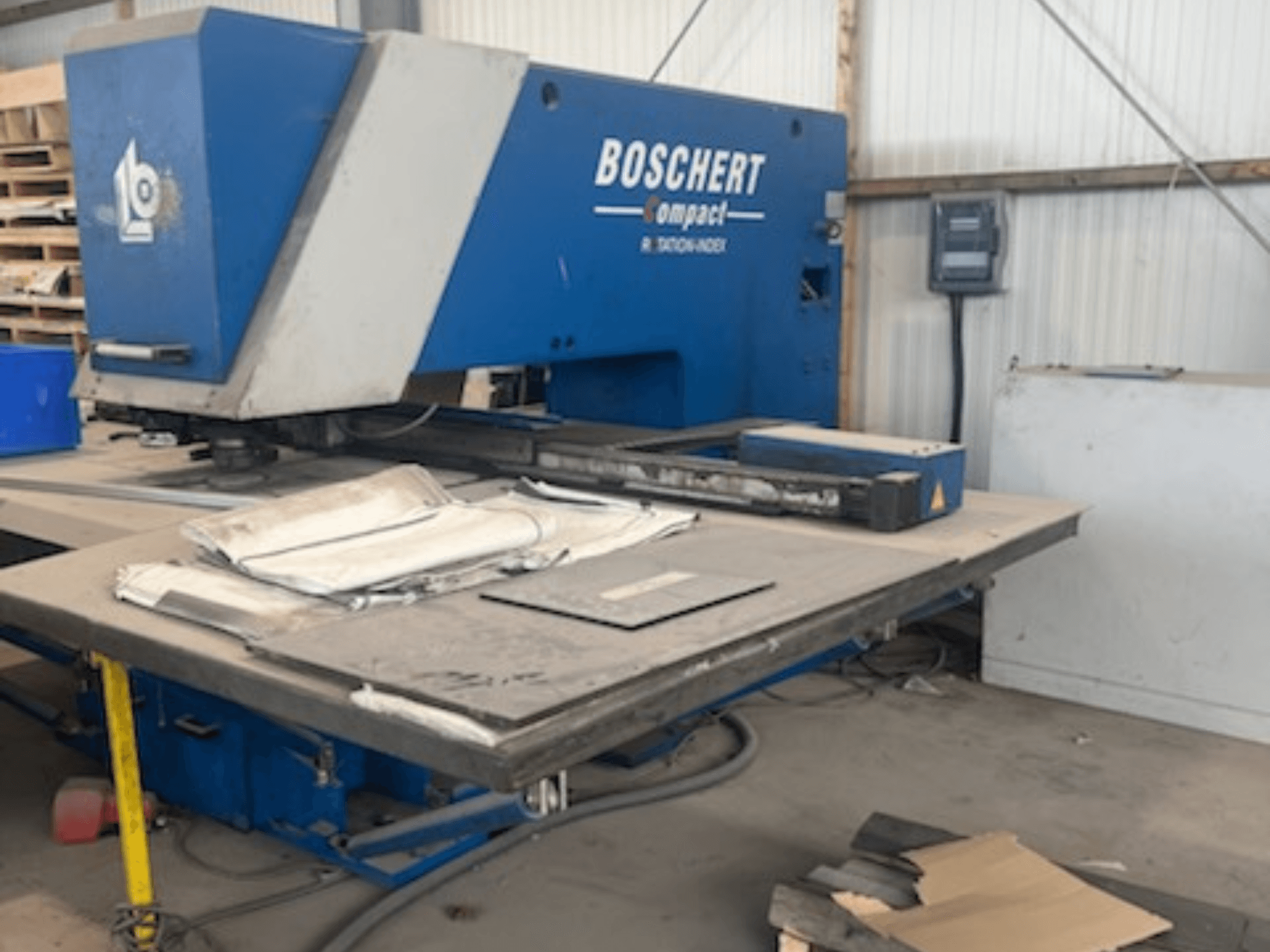 Punzonadora CNC BOSCHERT COMPACT 1000 en un taller, en la que se aprecia la vista frontal con chapas metálicas sobre la mesa.