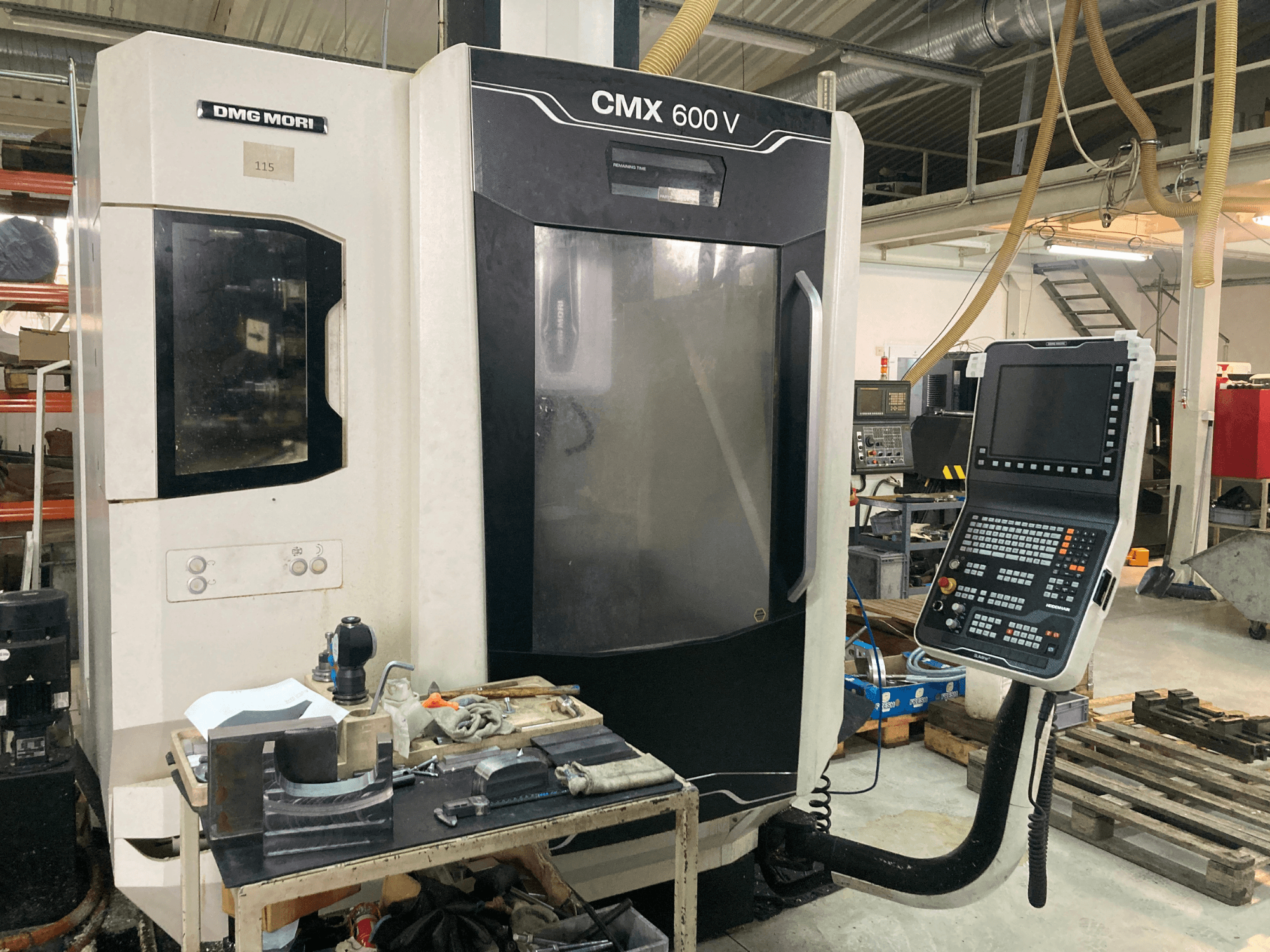 Fresadora DMG MORI CMX 600 V vista de frente, mostrando el panel de control y la mesa de trabajo con herramientas.