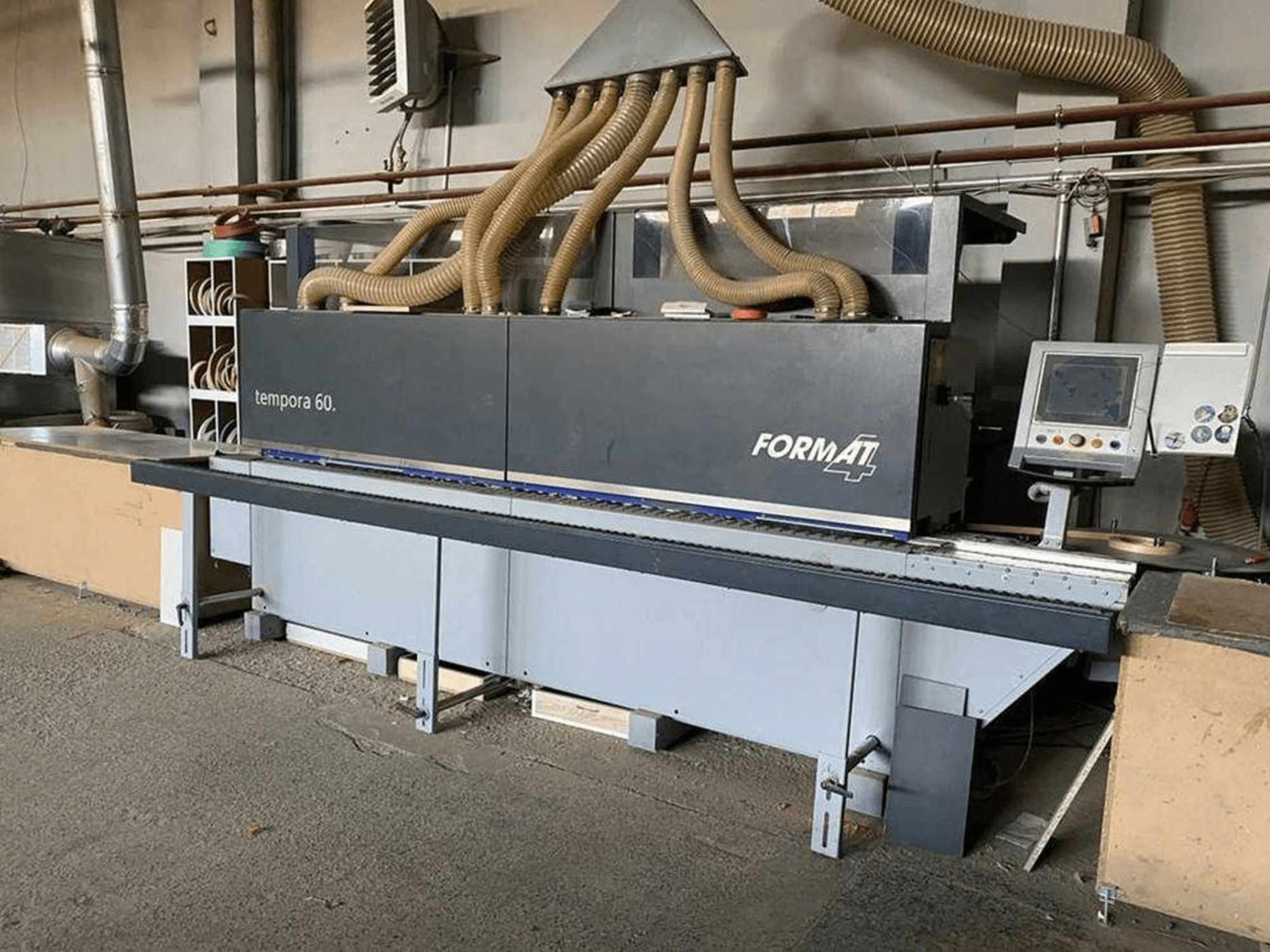 Encoladora de cantos FORMAT4 Tempora 60 en vista lateral, con múltiples mangueras y un panel de control con botones y pantalla.