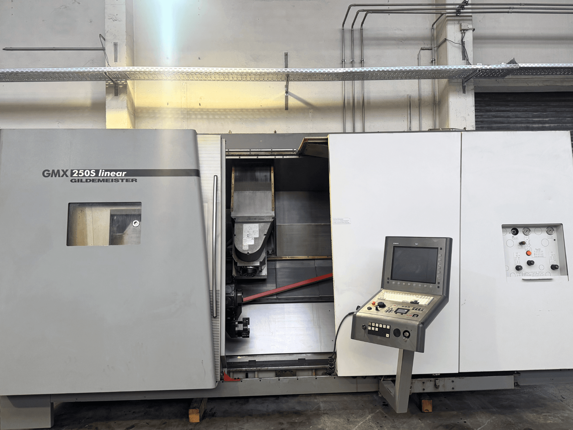Máquina CNC lineal Gildemeister GMX 250S, vista frontal, mostrando el panel de control y el área de trabajo abierta.