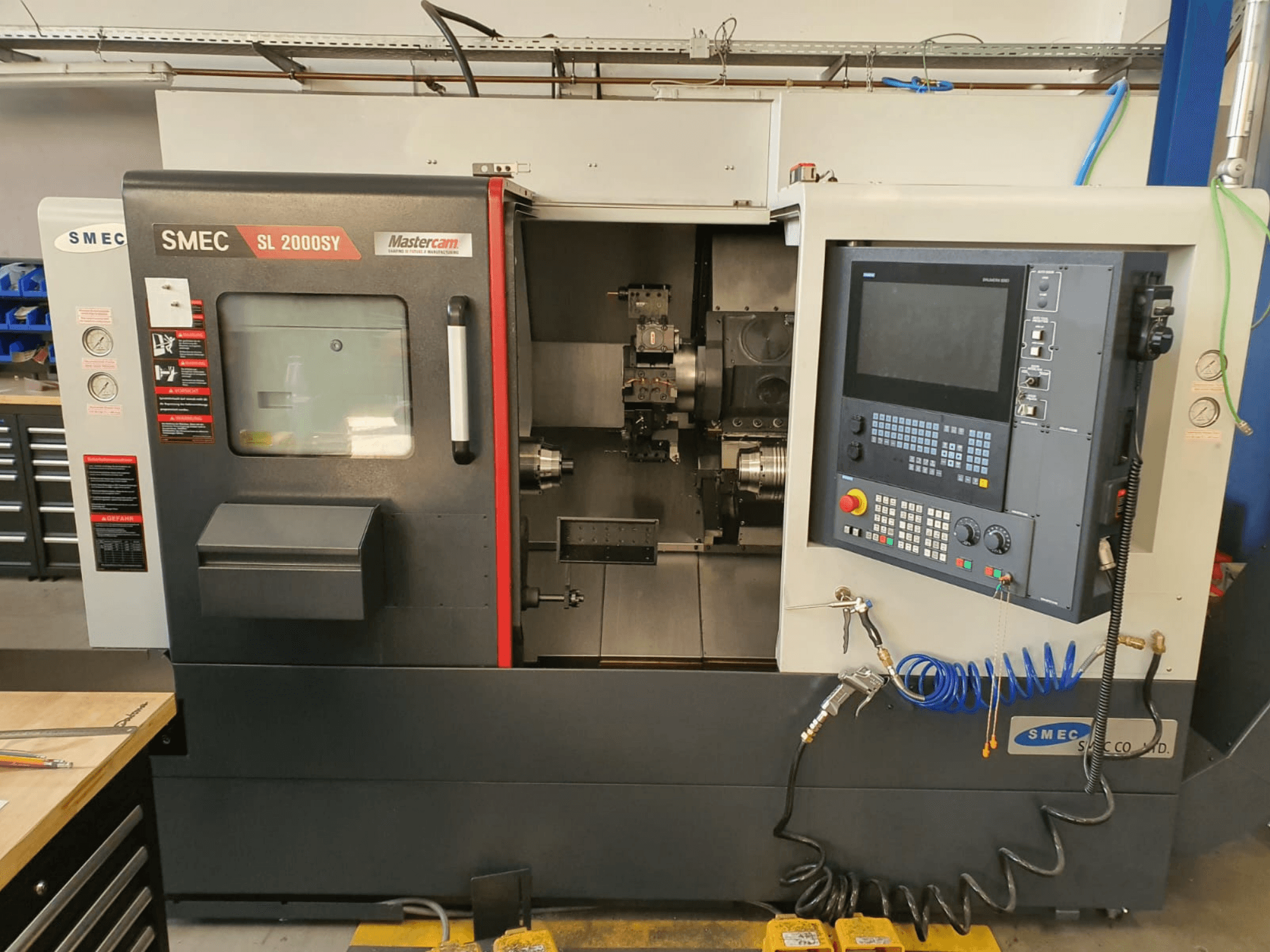Torno horizontal SMEC SL2000SY visto de frente, en el que se aprecian el panel de control, la pantalla y el portaherramientas.