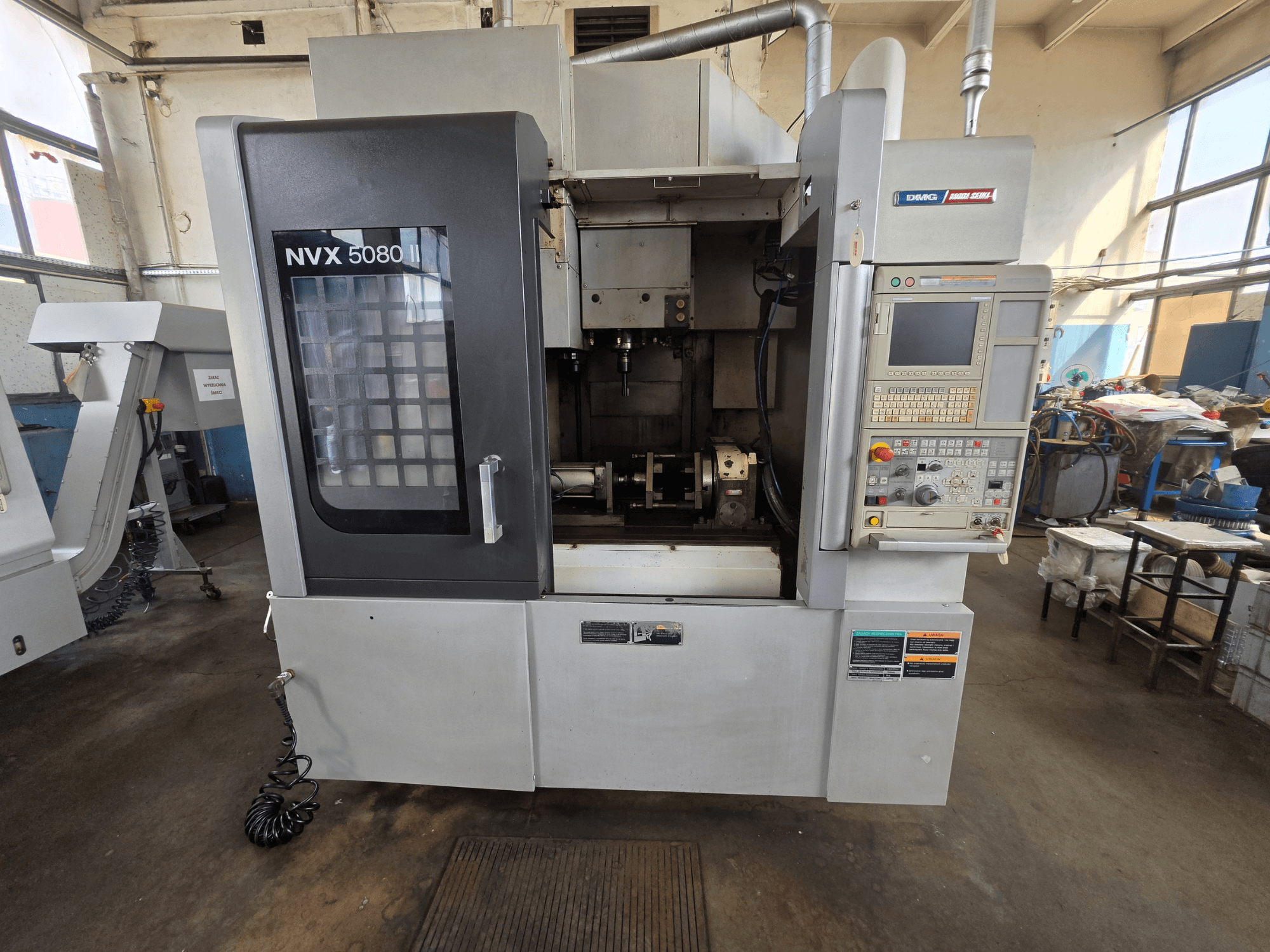 Vista frontal del centro de mecanizado vertical DMG Mori Seiki NVX 5080 II/40, con el panel de control y la ventana transparente, en la que se aprecia la zona de mecanizado.