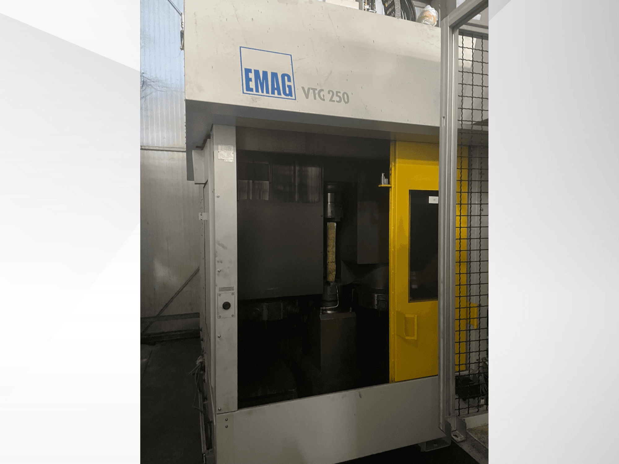 Centro de mecanizado vertical EMAG VTC 250 en vista frontal, con una puerta amarilla y una herramienta de corte visible dentro de la cámara.