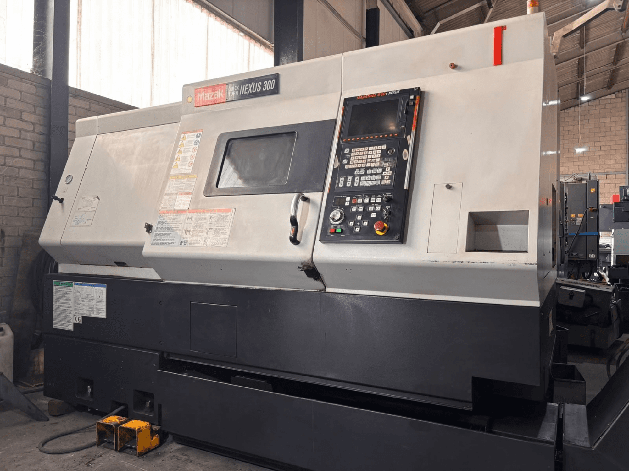 Torno horizontal Mazak QT NEXUS 300, vista lateral en la que se aprecian el panel de control y los indicadores de funcionamiento en un entorno de taller.