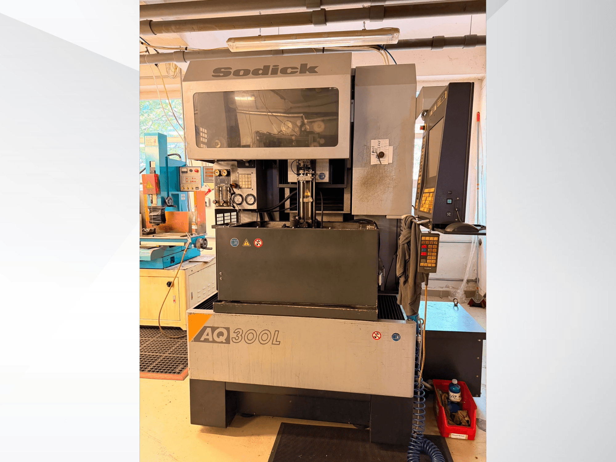 Máquina de electroerosión por hilo Sodick AQ300L, vista frontal, en la que se aprecian el panel de control, la zona de trabajo y los indicadores de seguridad.