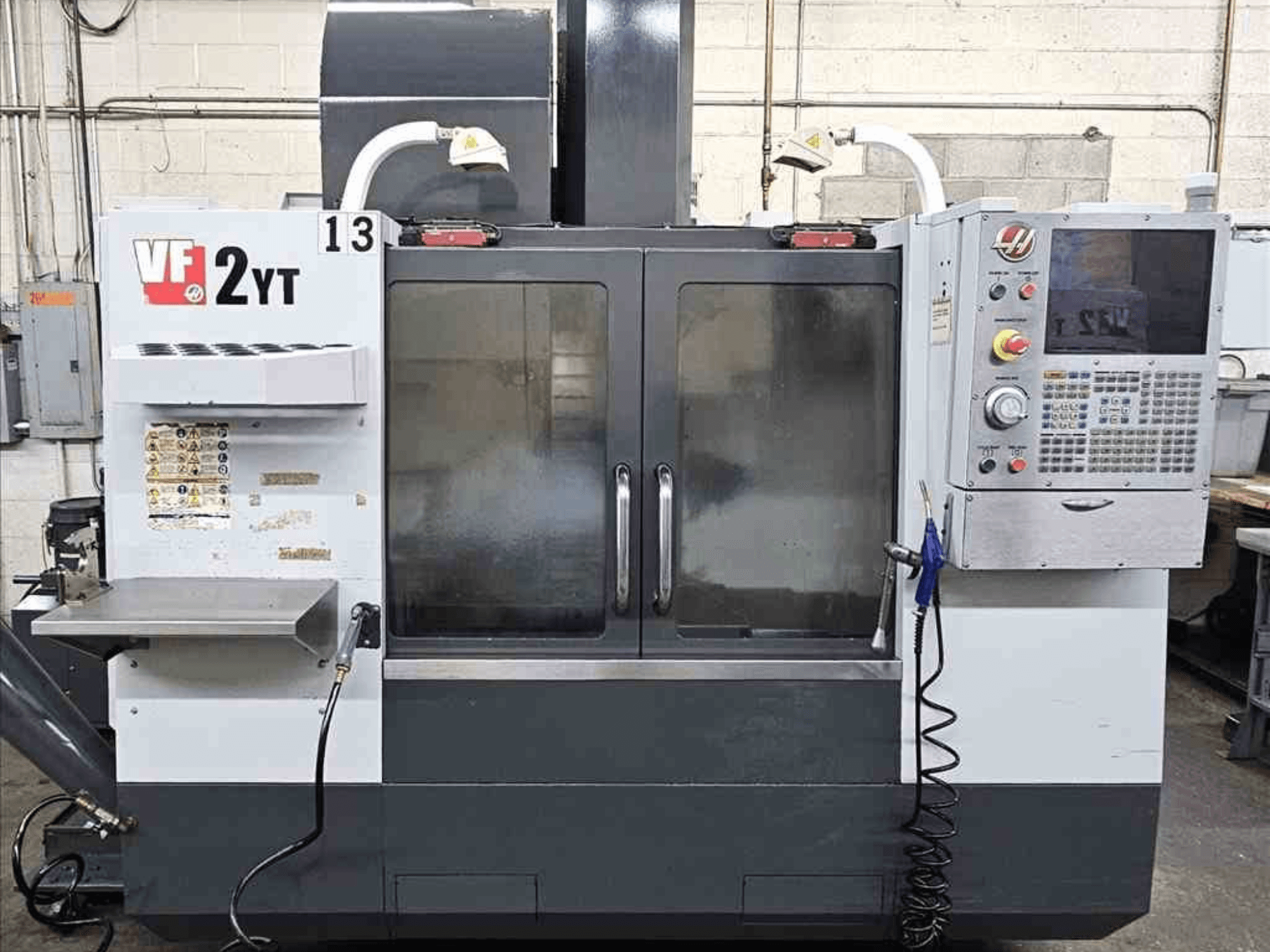 Vista frontal de un Centro de Mecanizado Vertical HAAS VF-2YT, mostrando el panel de control y las puertas de cristal.