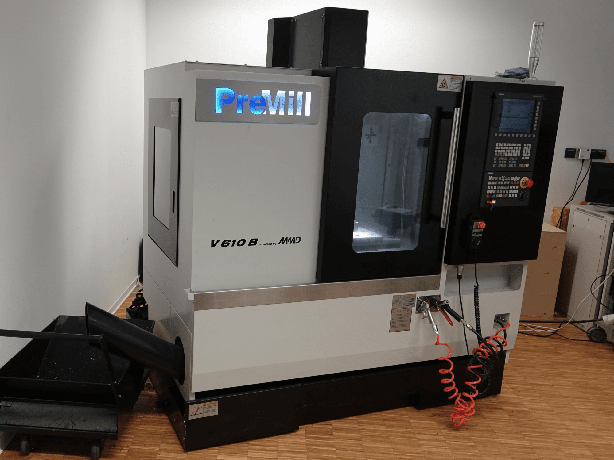 Centro de mecanizado vertical PreMill V 610 B, vista frontal, en la que se aprecian el panel de control, el sistema de refrigeración y las mangueras de aire conectadas.