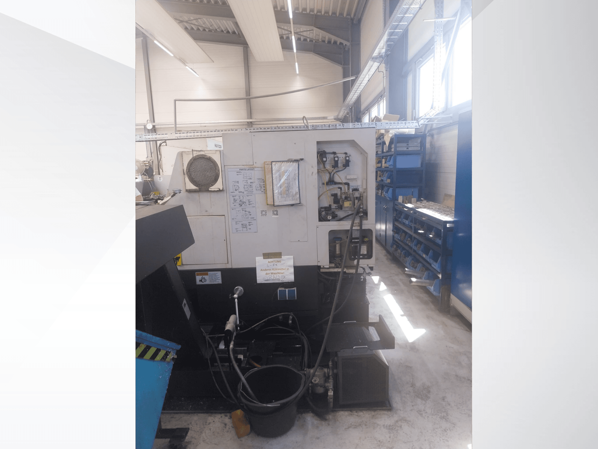 Mazak QUICK TURN NEXUS 200 MS, vista lateral en la que se aprecian el panel de control, las mangueras y la zona de herramientas en un entorno de taller.