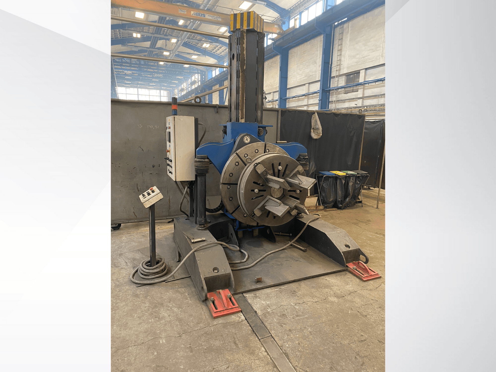 Torno industrial azul con cabezal giratorio redondo y panel de control, vista lateral, en un taller.