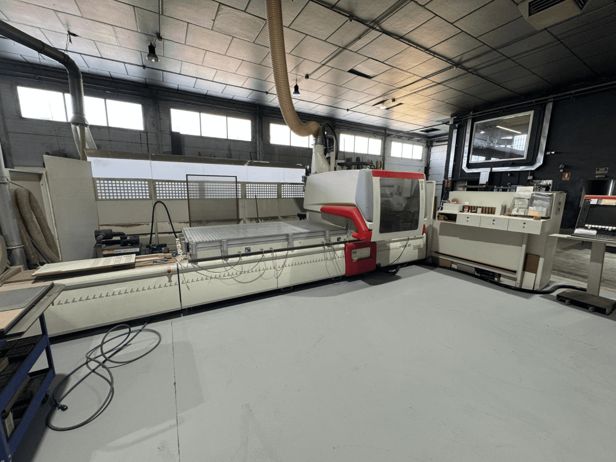 Máquina CNC en un taller, vista frontal con acentos rojos, equipada con panel de control y superficie de trabajo, para corte de precisión.