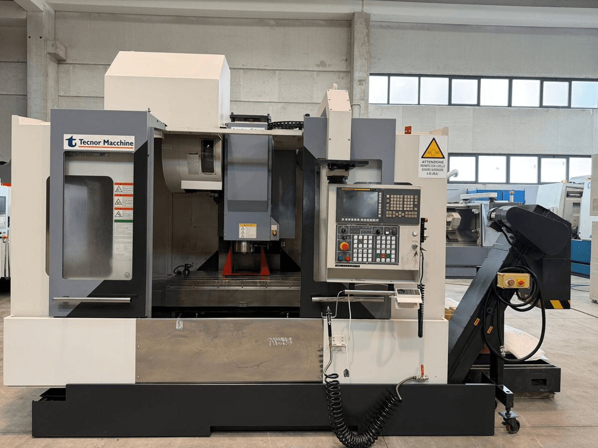 Fresadora CNC Tecnor Machine, vista frontal, presenta panel de control con botones, etiquetas de advertencia y portaherramientas.