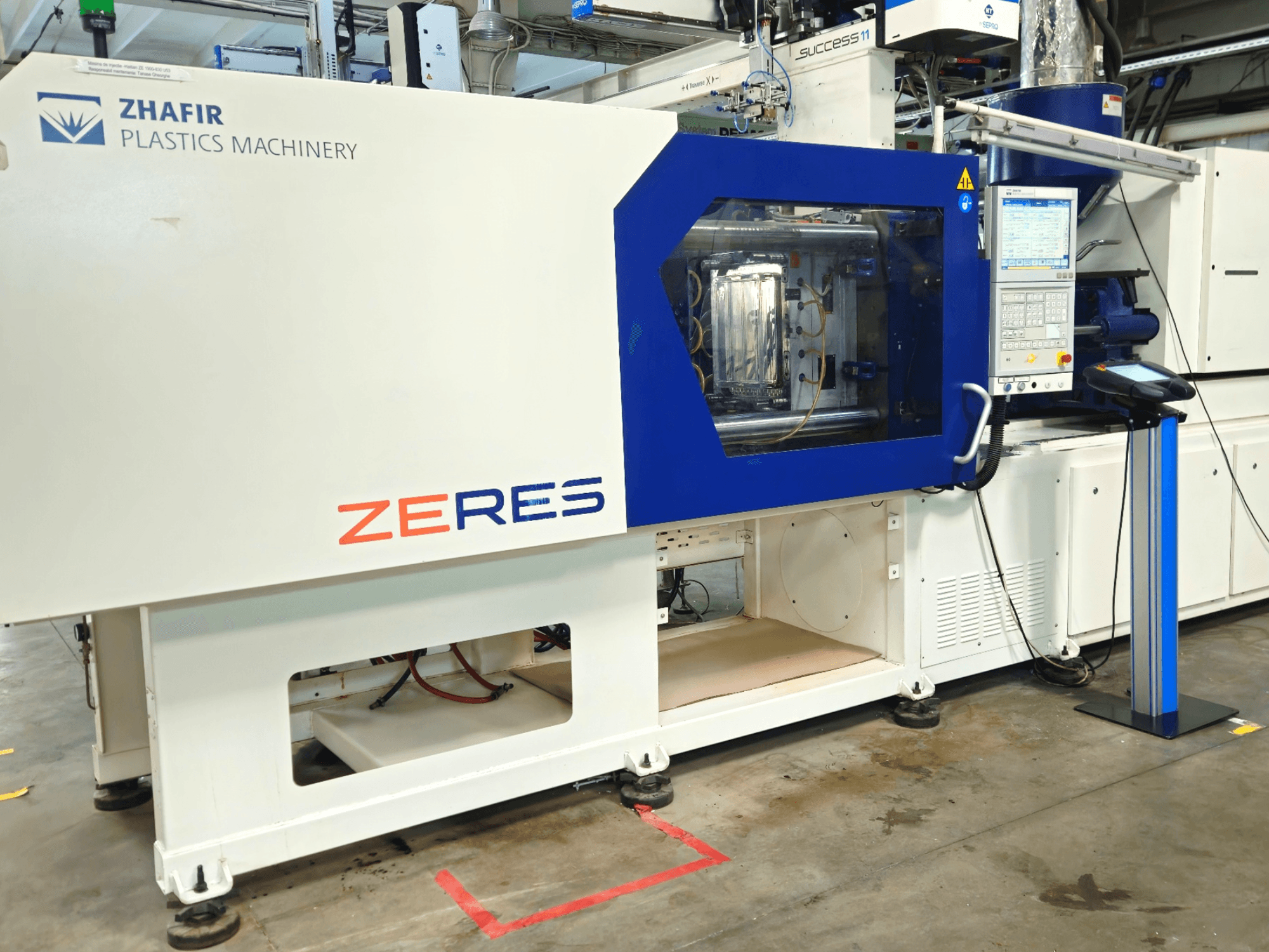 Máquina de moldeo por inyección Zhafir Zeres en vista frontal, con panel de control y zona de moldeo transparente.