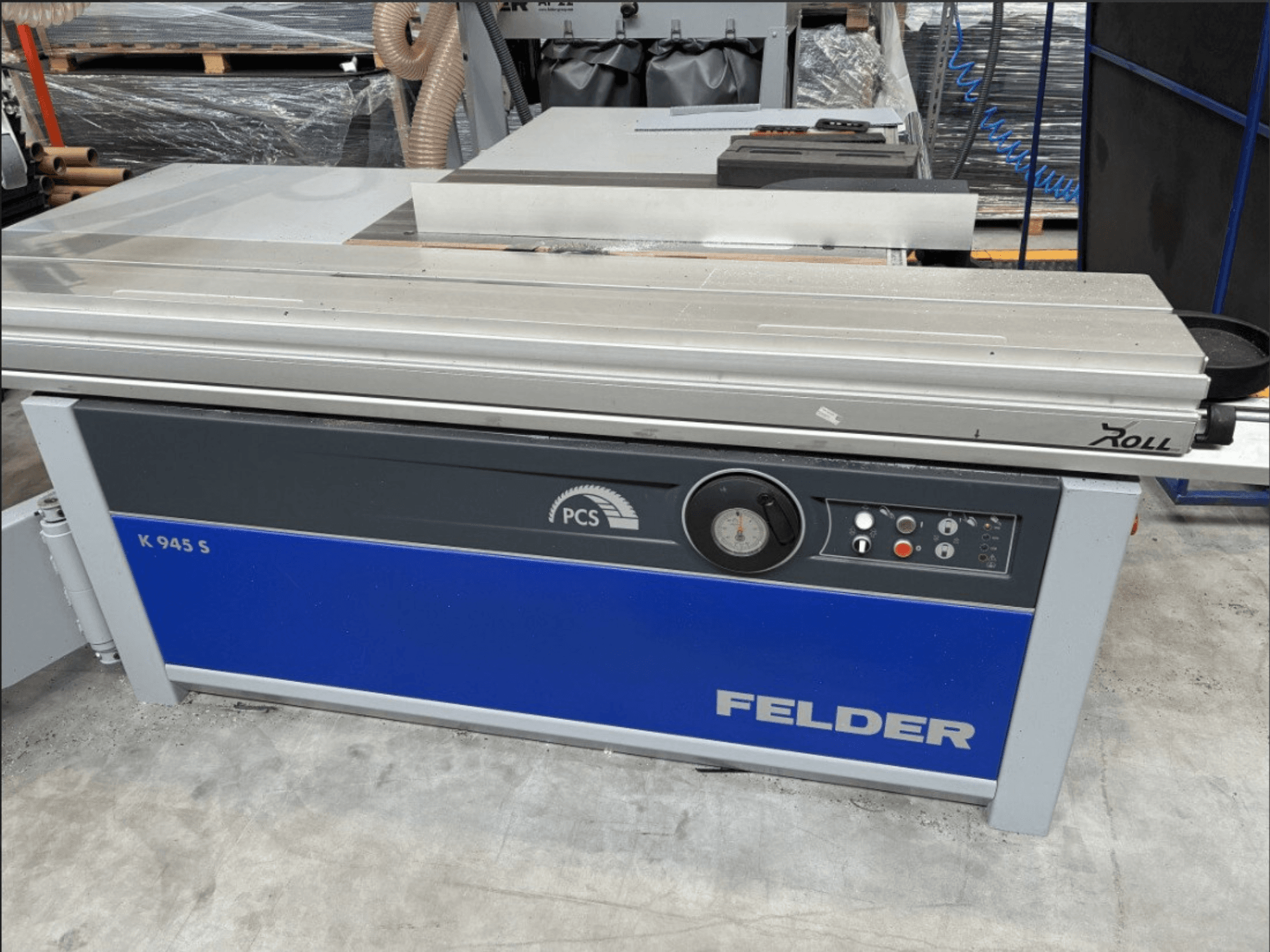 Sierra para paneles FELDER K 945 S, vista frontal en la que se aprecian el panel de control, la mesa y los dispositivos de seguridad, instalada en el suelo de un taller.
