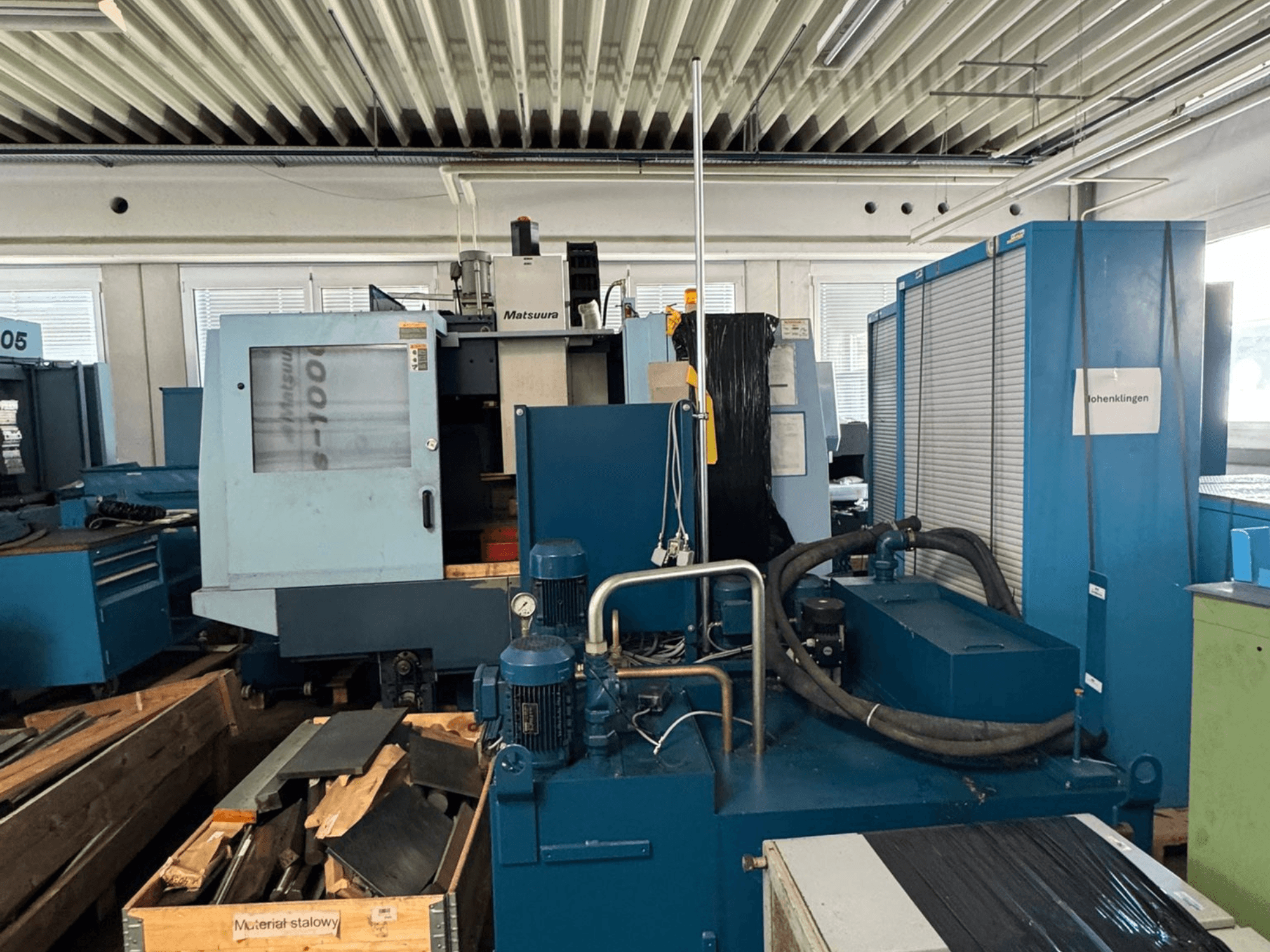 Vista frontal del centro de mecanizado vertical Matsuura Vplus 1000/40, en la que se aprecian los controles, los motores y el entorno del taller que lo rodea.
