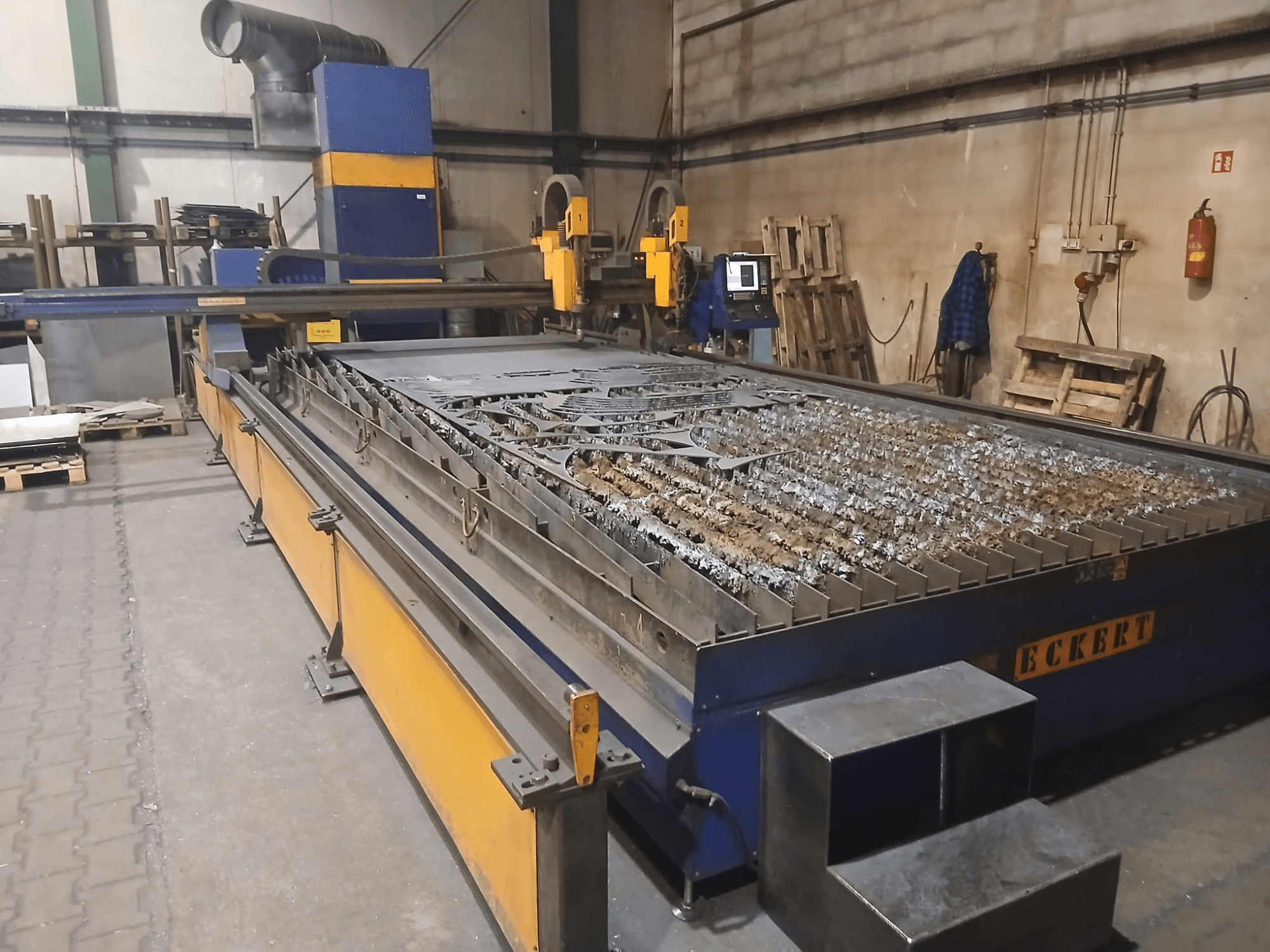 Máquina de corte por plasma ECKERT JANTAR 2 vista de frente, que cuenta con una amplia mesa de corte con piezas metálicas y los mandos de control.