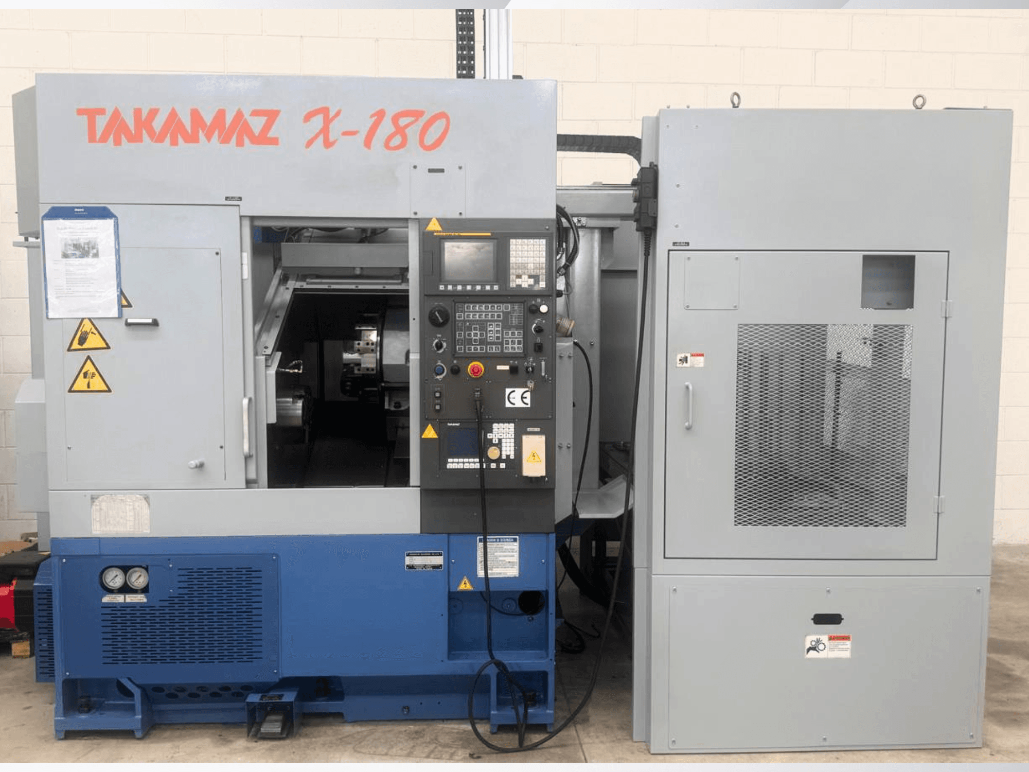 Torno horizontal Takamaz X-180, vista frontal en la que se aprecian el panel de control, las etiquetas de seguridad y la unidad de refrigeración adyacente.